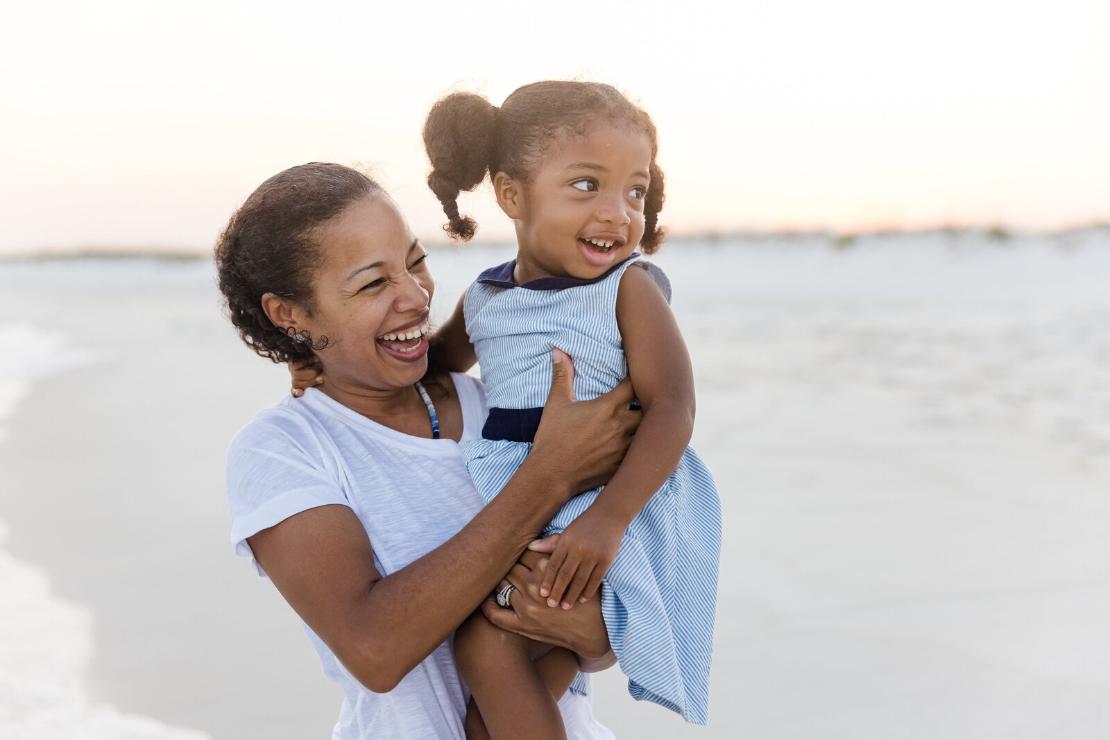 Mother and daughter laughing together during family beach trip photo session