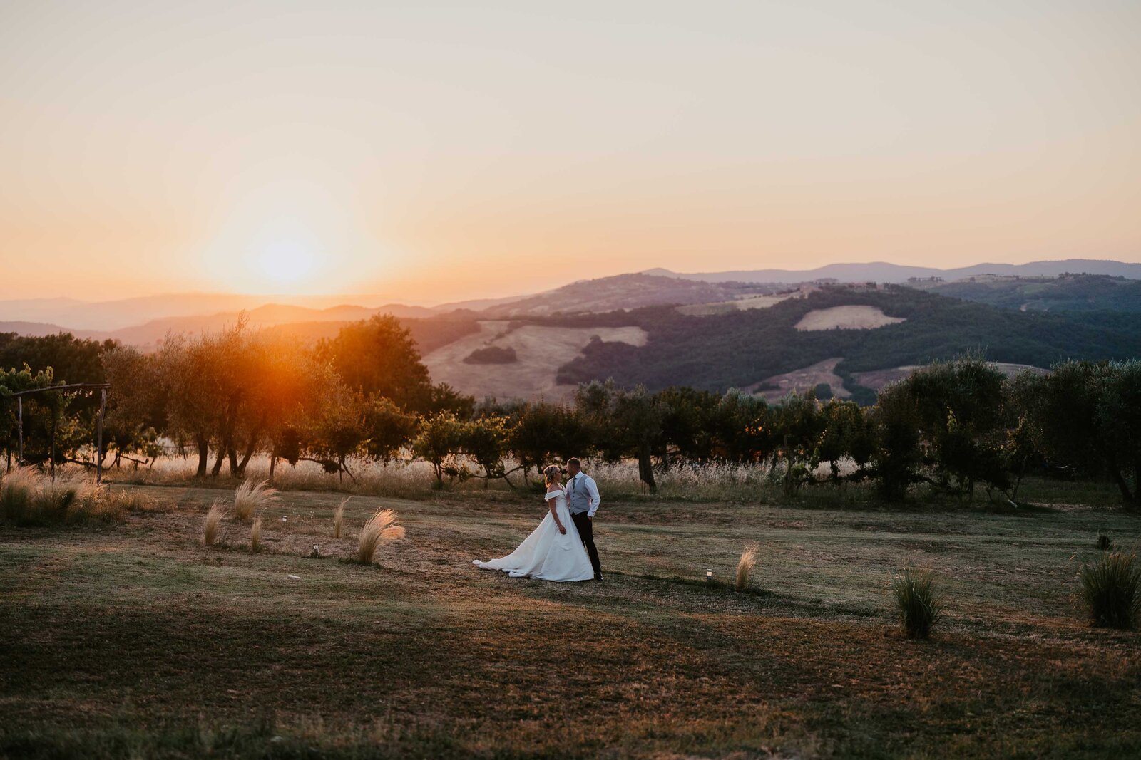 Bride and groom hug during golden hour in French field