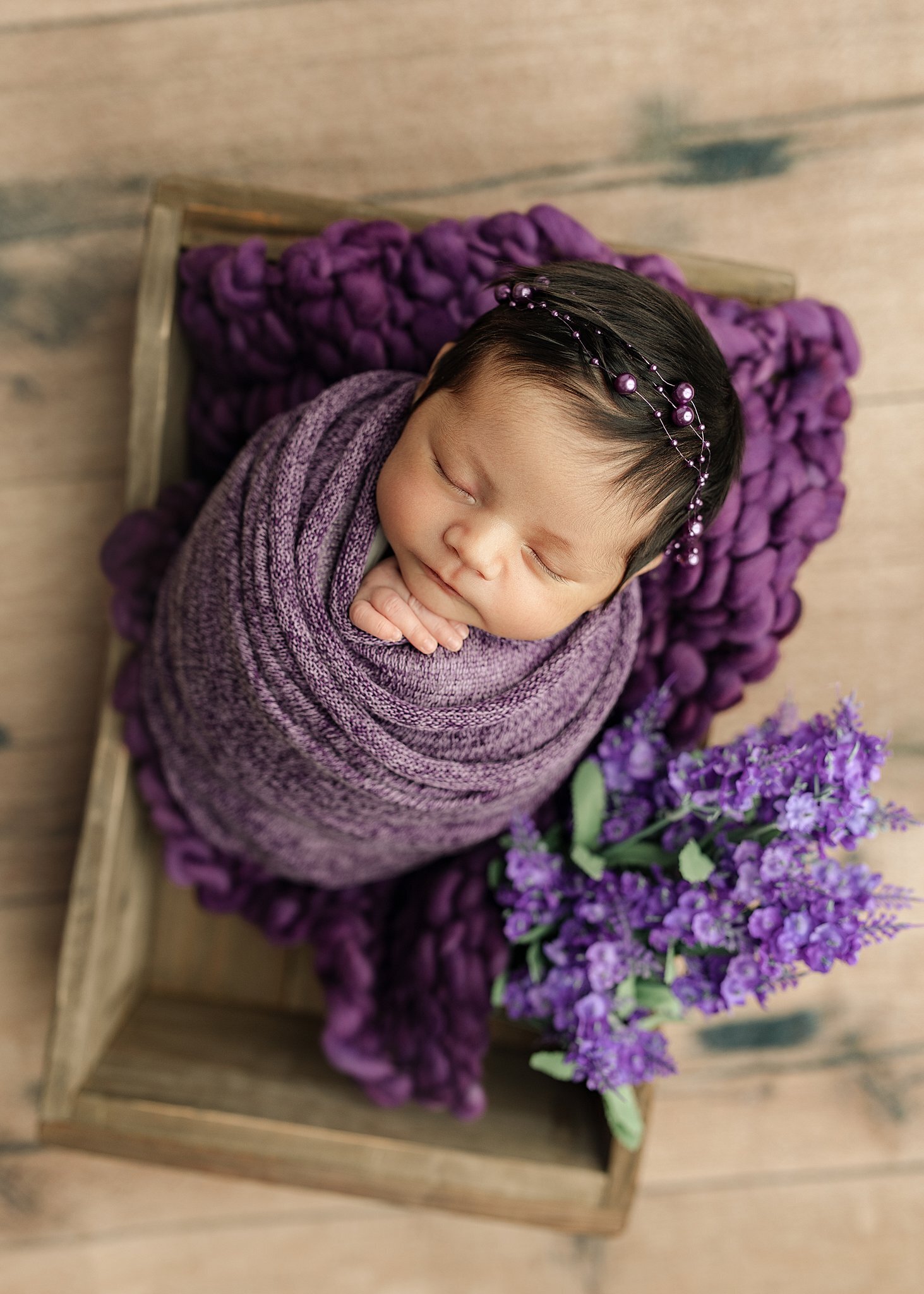 Quad city Newborn baby wrapped in purple, in a box prop with flowers