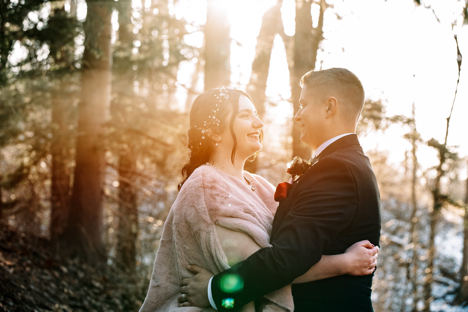 a bride and groom embrace as they are engulfed in gorgeous sunlight coming through the trees in boyce park