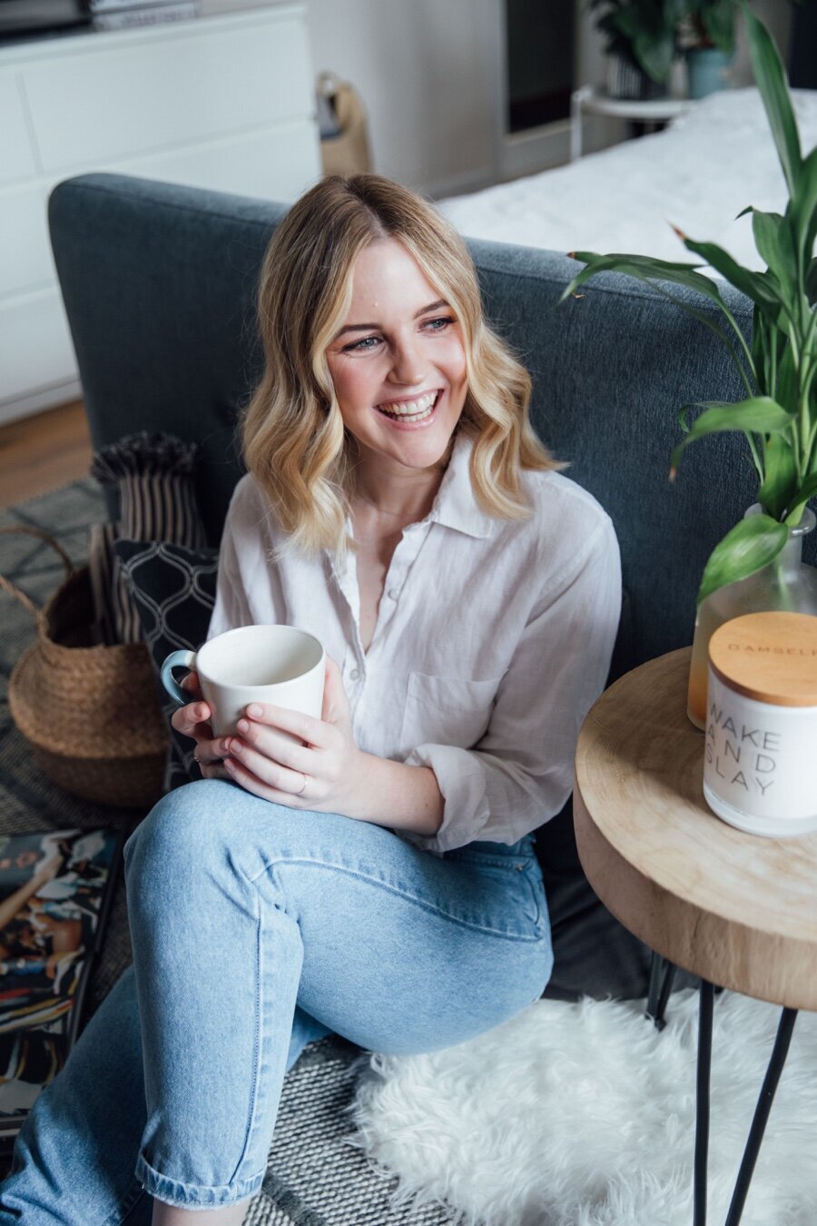 Lifestyle shot of woman smiling and drinking coffee in bedroom. Image for hair salon