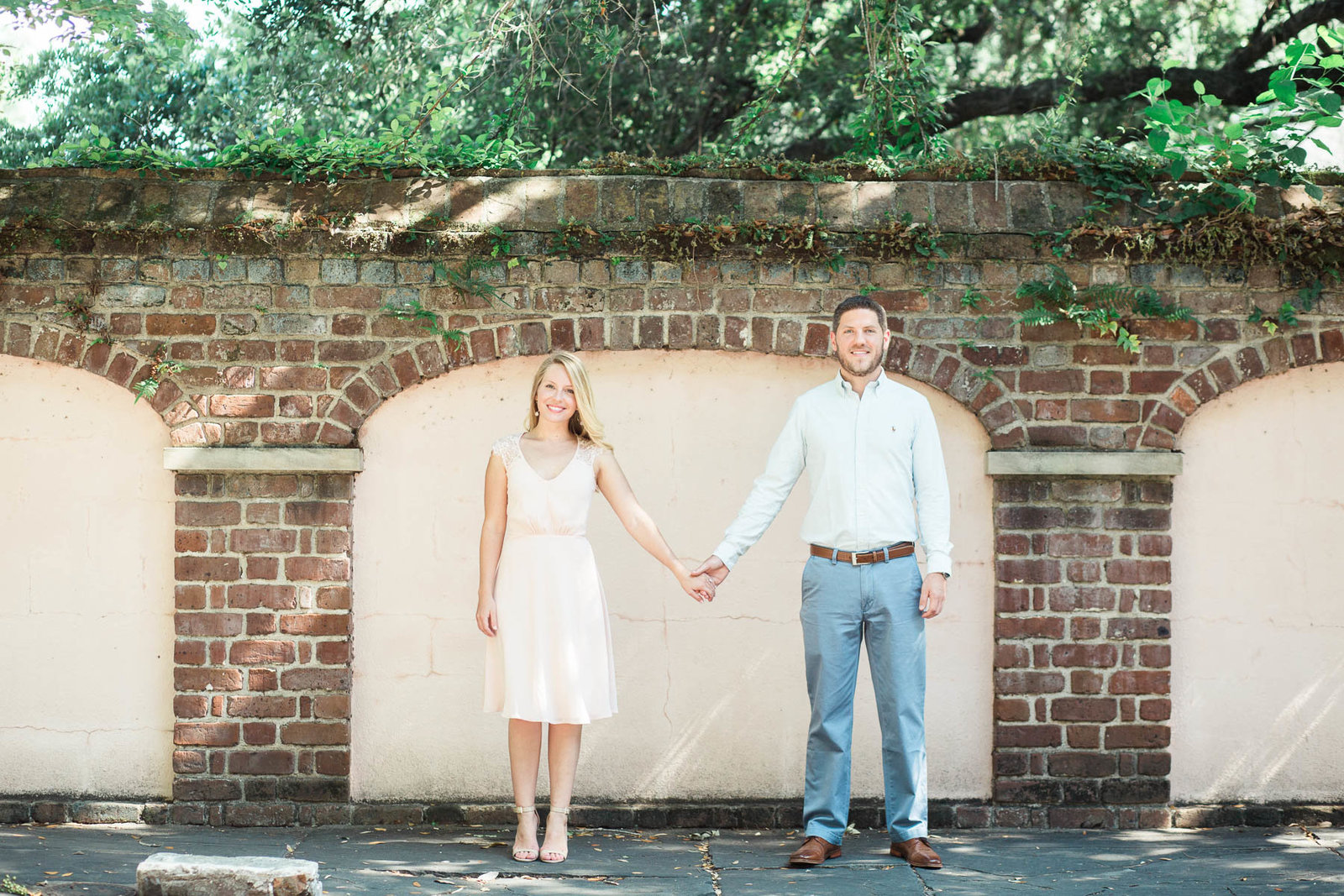Engaged couple stands in front of brick wall, Downtown Charleston, South Carolina