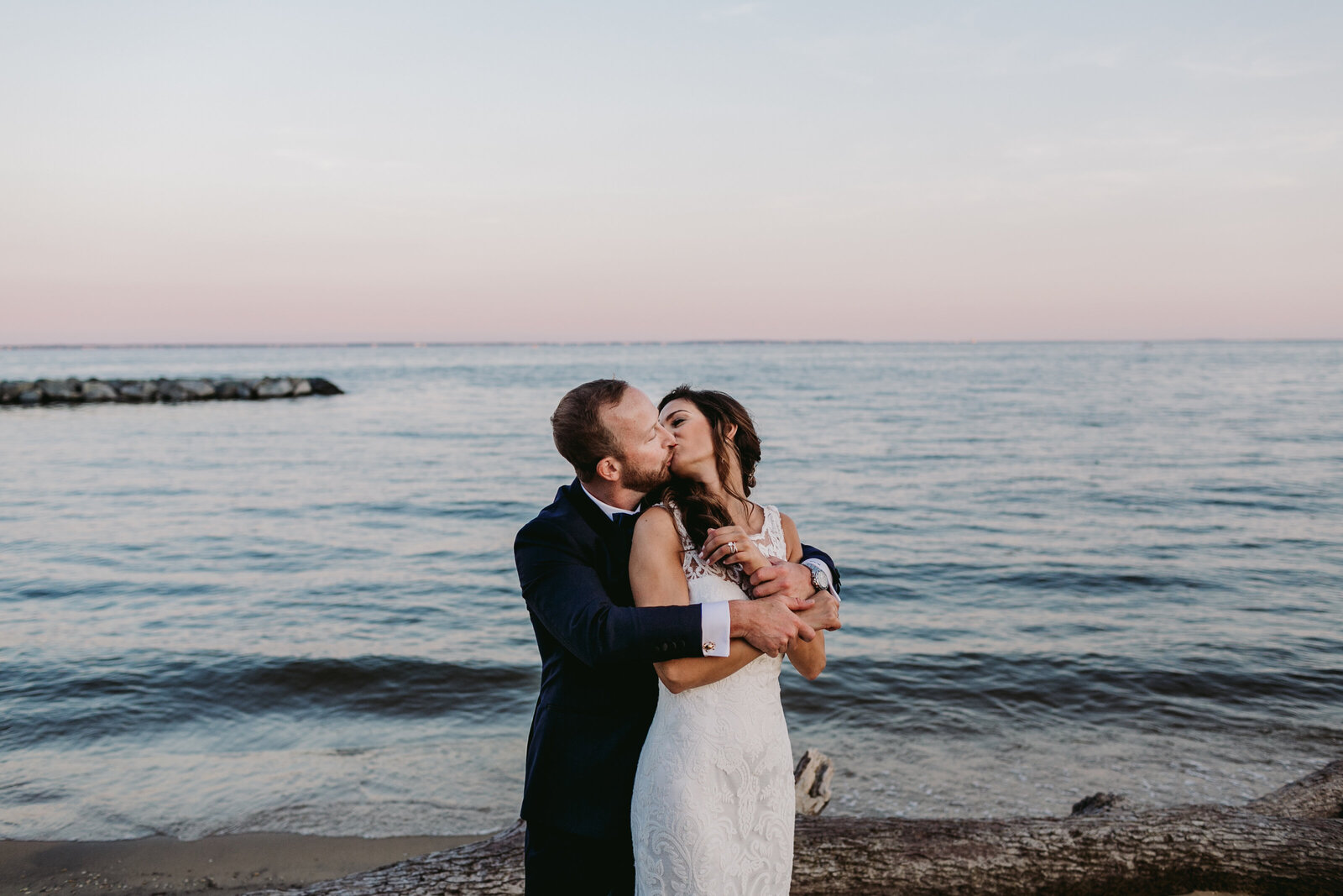 bride and groom kissing at beach sunset