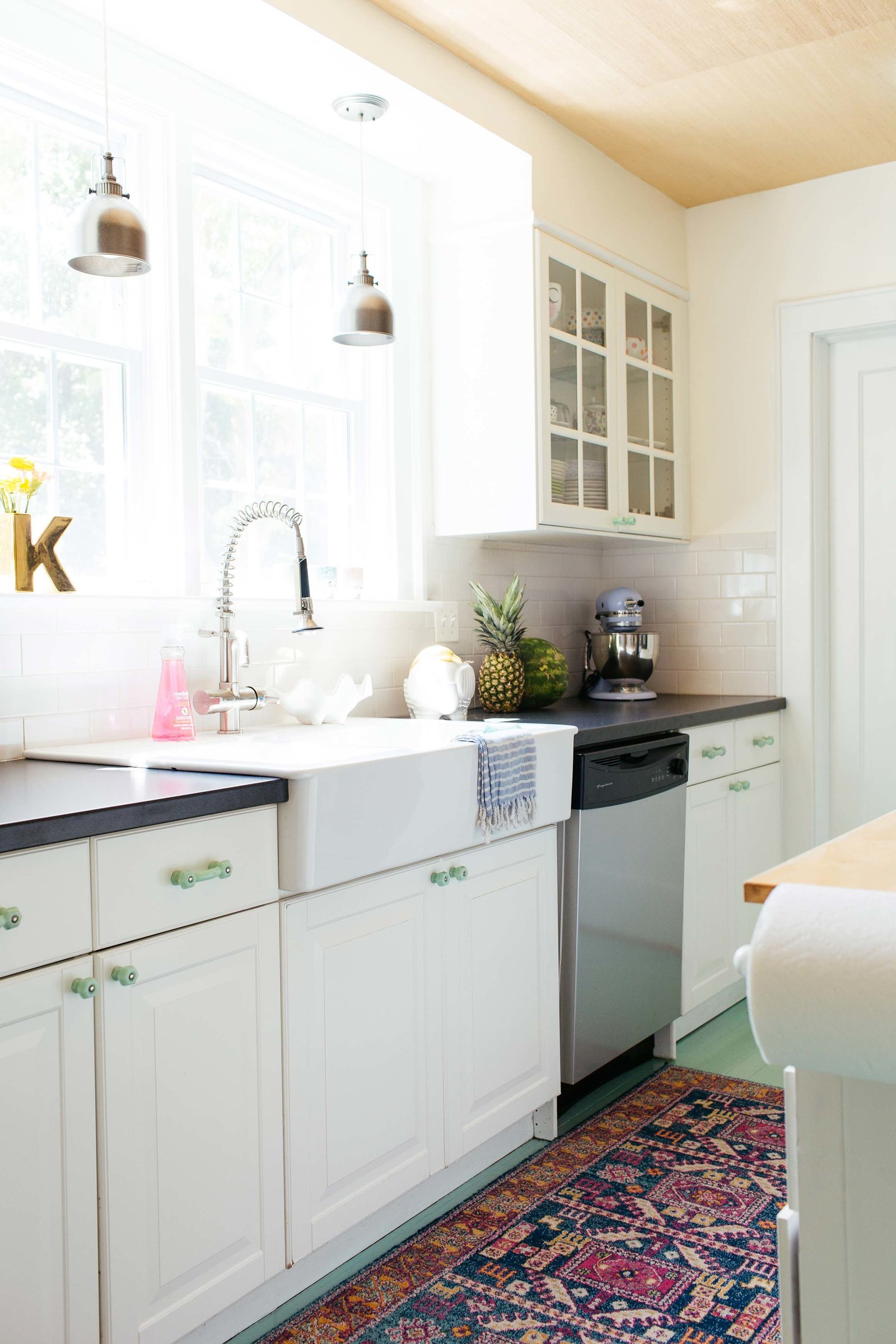 A small kitchen with mint floors and white cabinets.