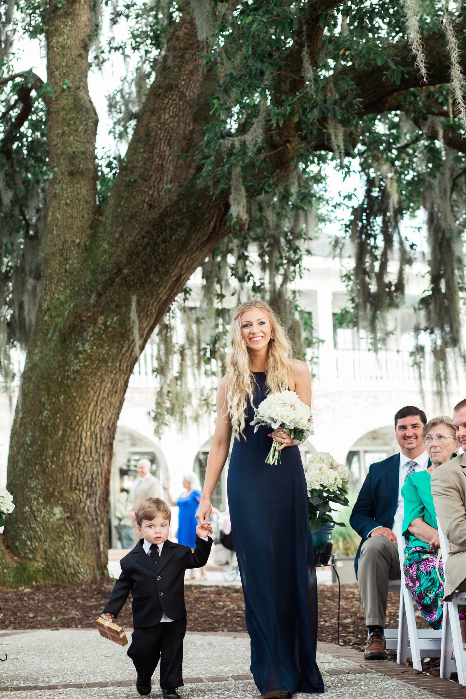 Bridesmaid and ring bearer walk down the aisle, Dunes West Golf and River Club, Charleston Wedding Photographer.