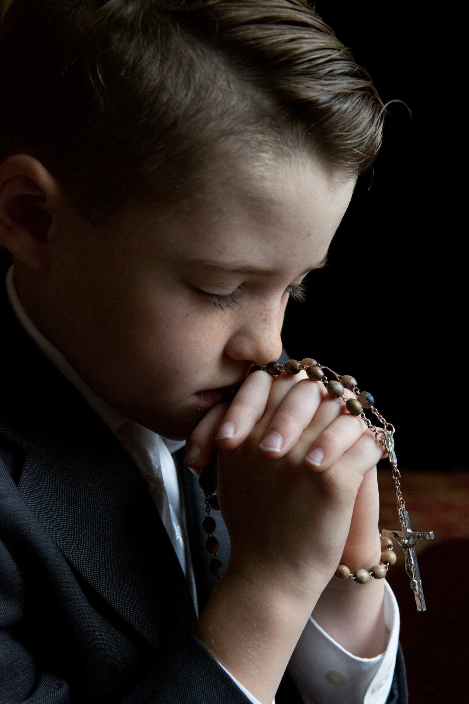 young boy prays with his eyes closed hands folded with a rosary Pomona Rockland County  baptism photographer Milestone Images