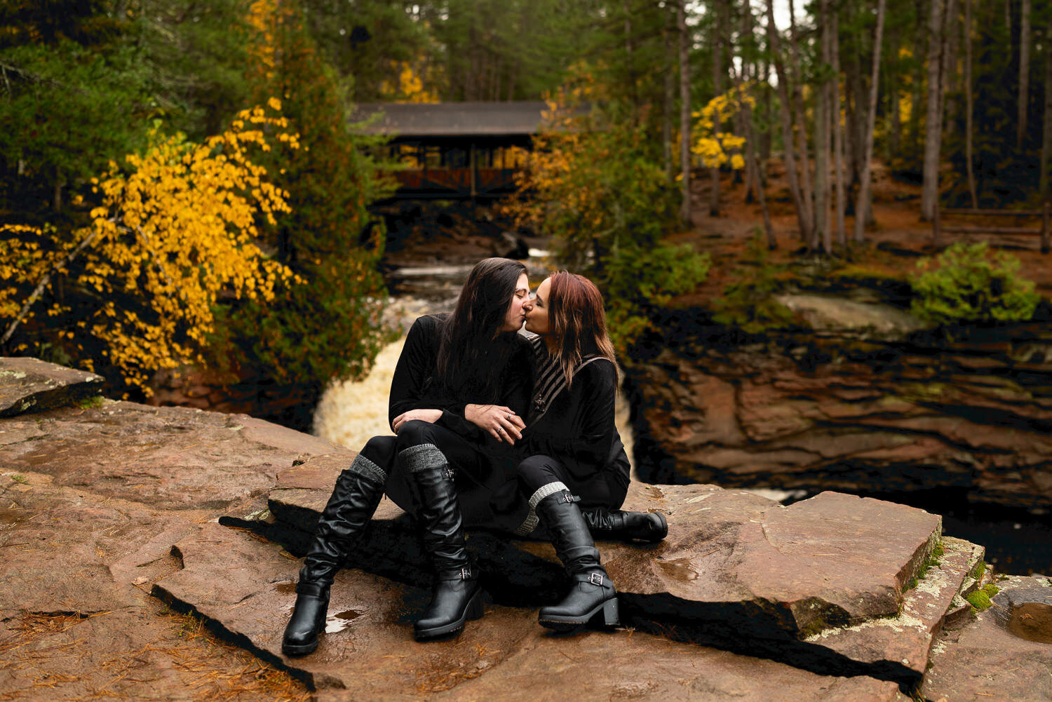 Lesbian couple kiss on a rock on a fall day in Wisconsin.