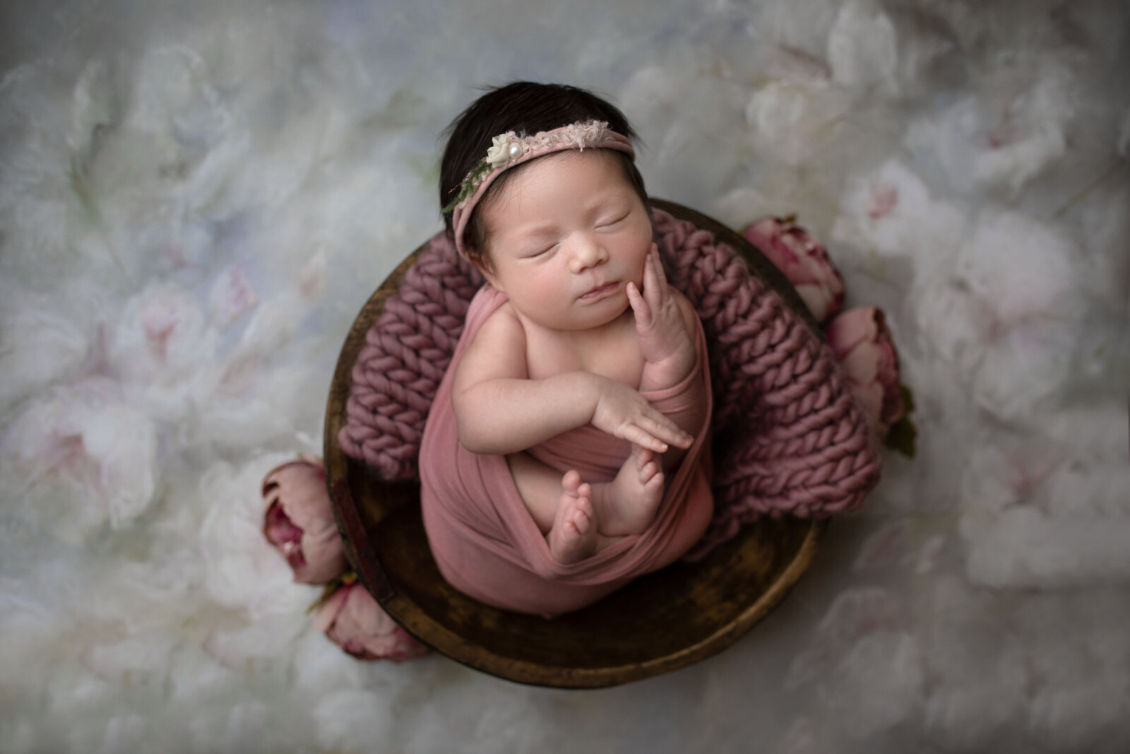 baby girl in brown bowl with flower backdrop