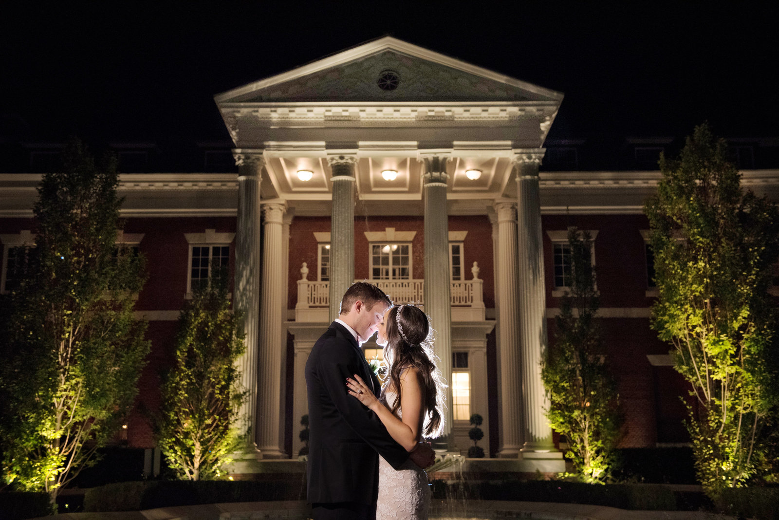 The front of the Bourne Mansion with the bride and groom kissing