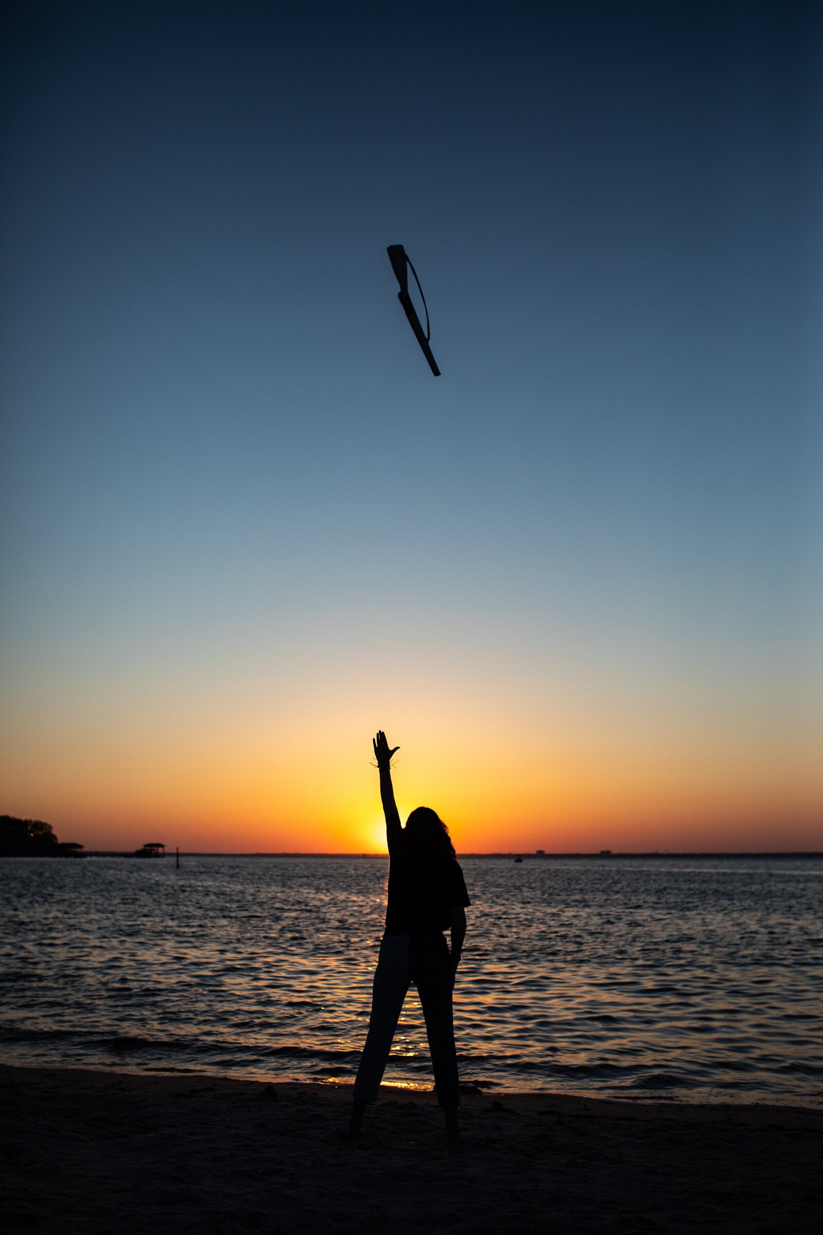 Senior girl silhouette of throwing colorguard rifle at Pensacola Beach