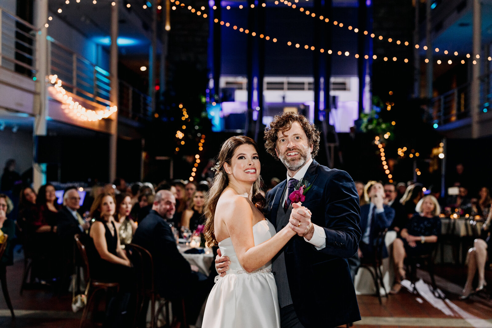 bride and groom dancing string lights