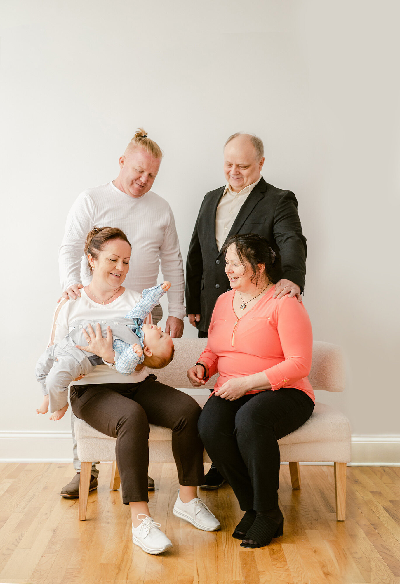 Both sets of grandparents playing with their one year old grandson during studio portraits