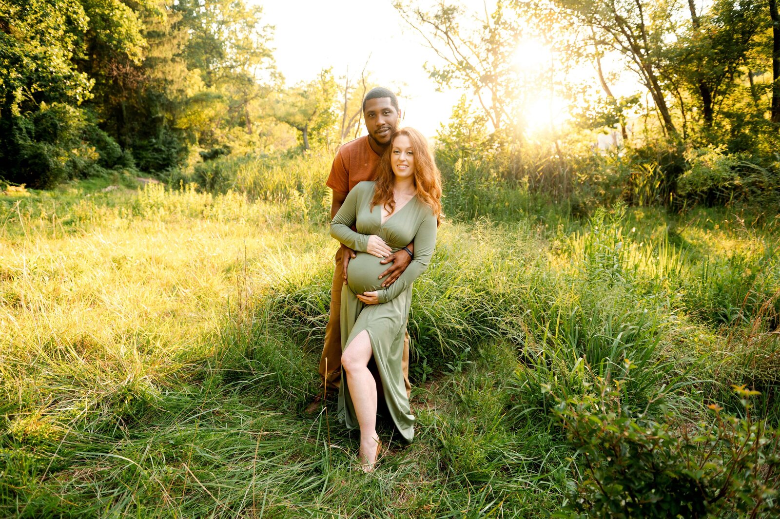 husband and pregnant wife in grass field
