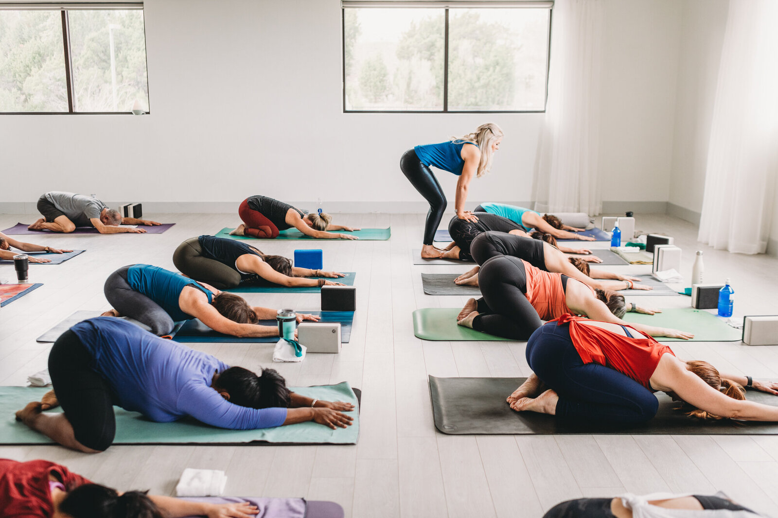 Branding Photographer,  a yoga teacher instructs a room full of people, all of them in yoga poses