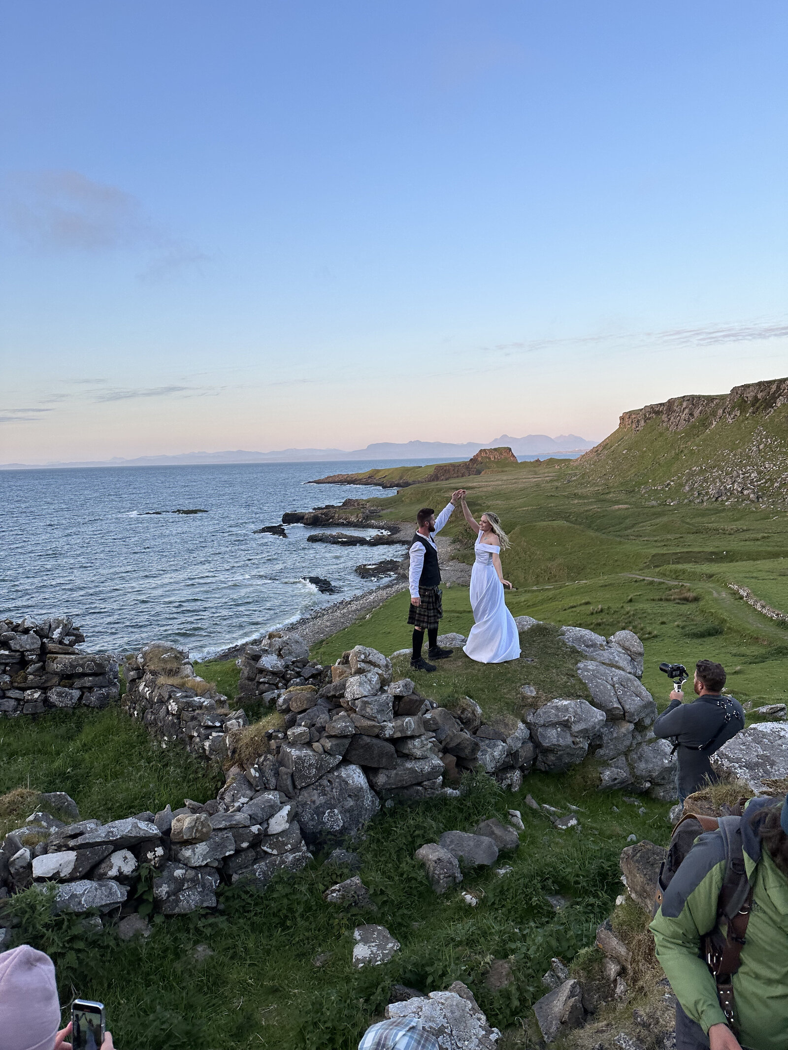 A couple dances by the sea on rocky ruins, with photographers capturing the moment at sunset—an inspiring scene from an Oregon coast photography retreat for wild-hearted artists.