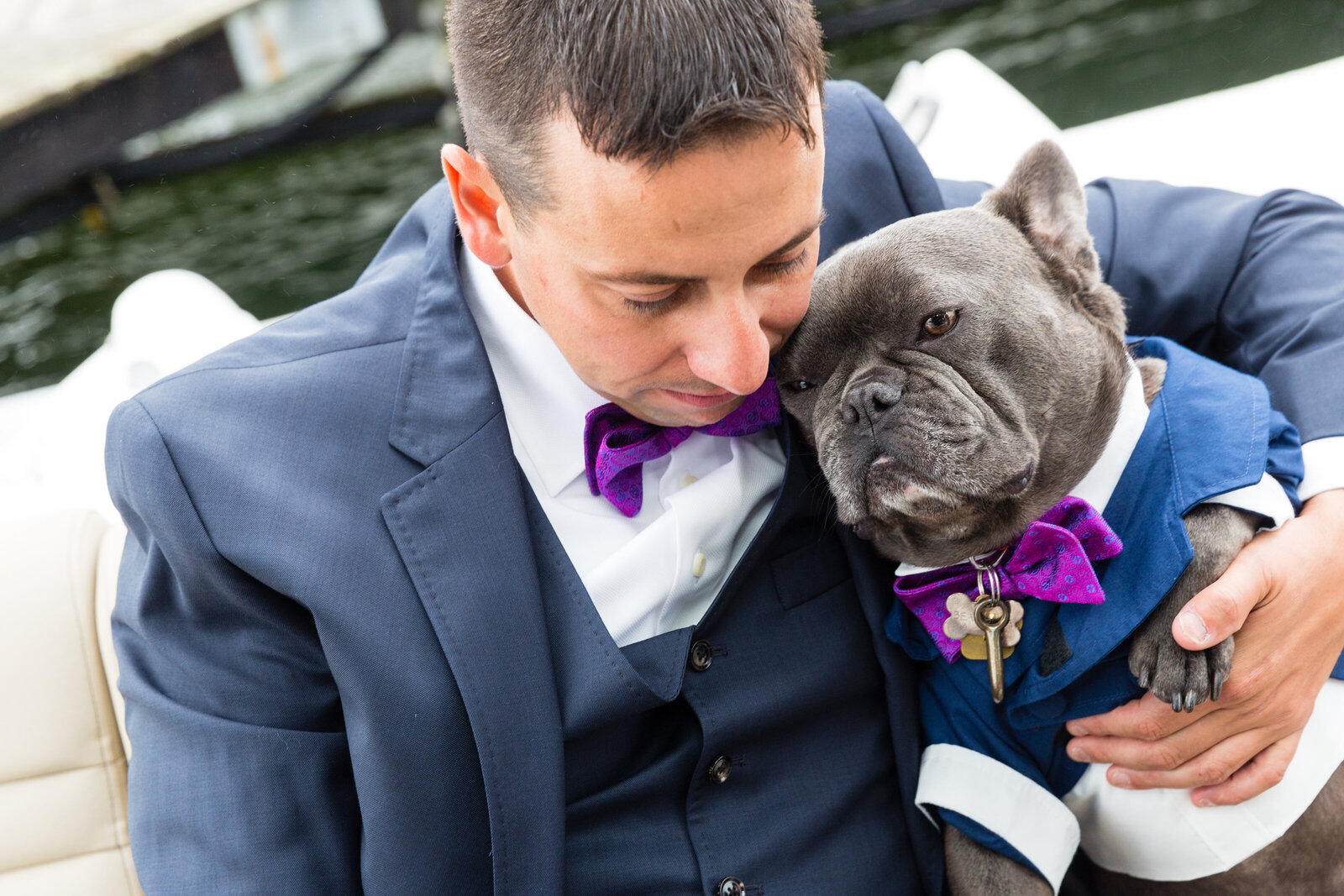 groom cuddles with dog wearing matching tuxedo