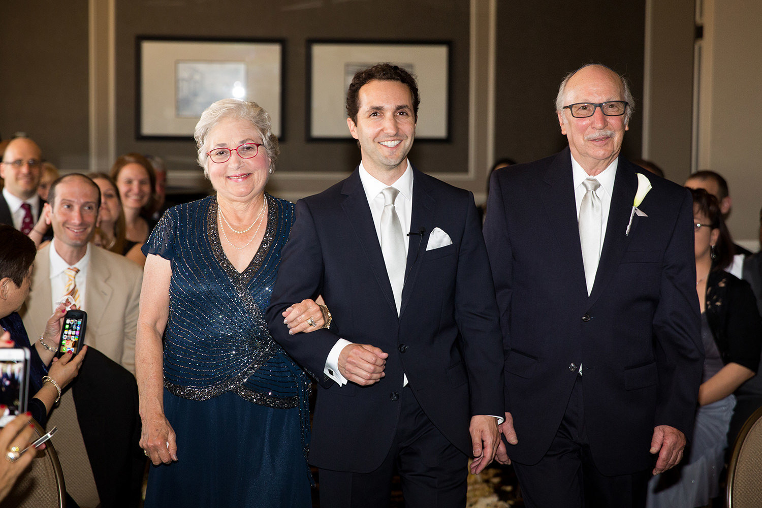 groom with parents walking down the aisle