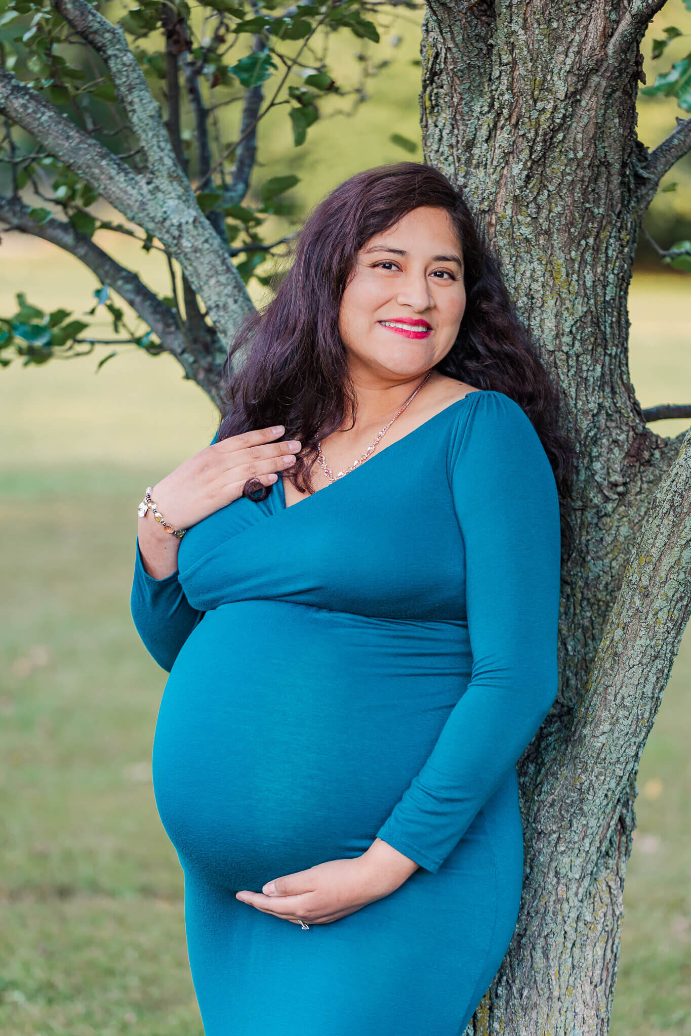 A Burke maternity session of a mom in a blue dress posing against a tree.