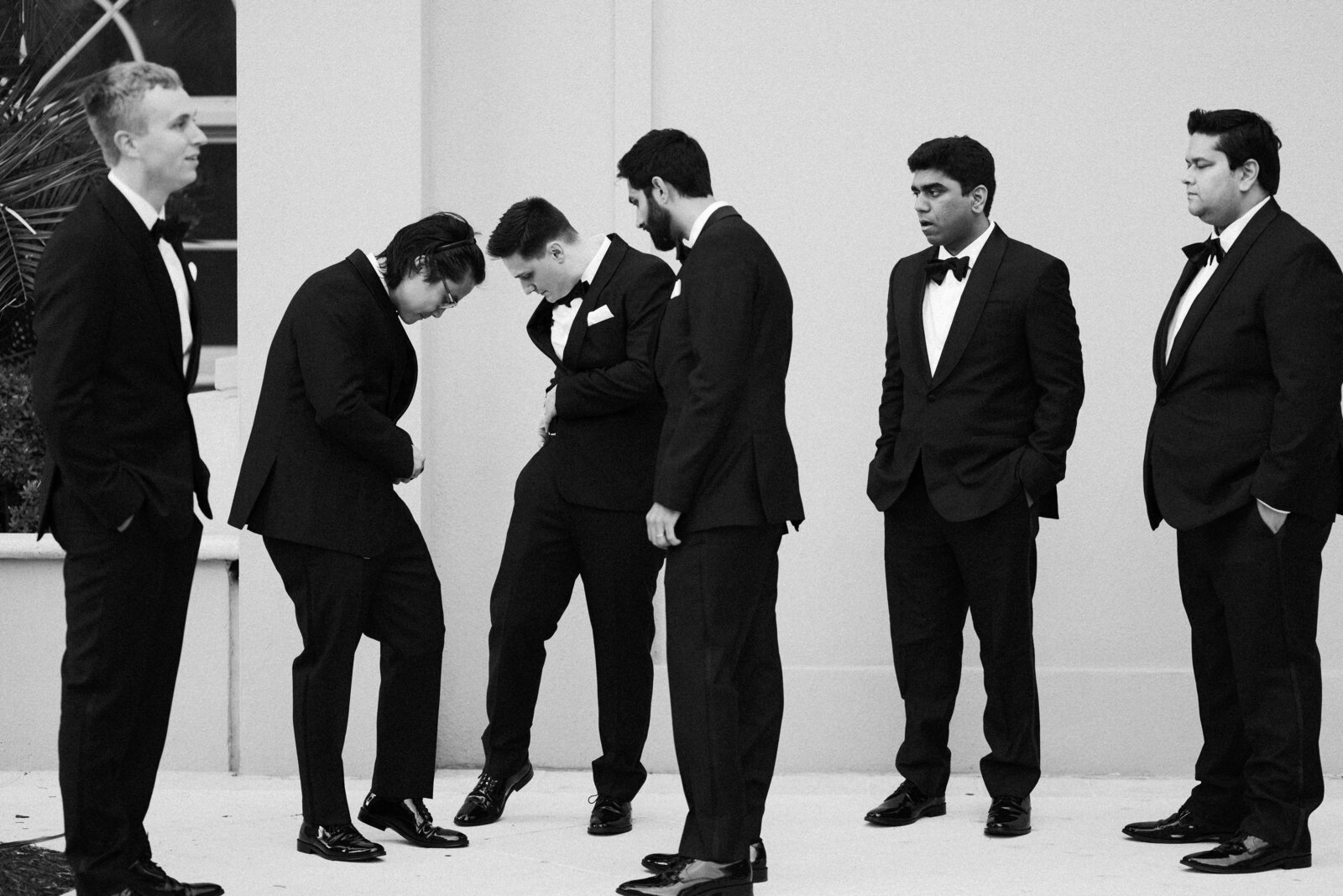 black and white photograph of groomsmen in black tuxedos  waiting for the groom