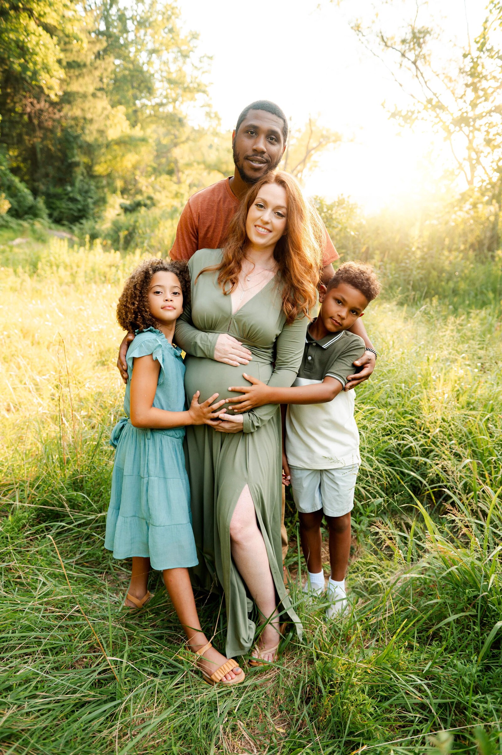 family of 4 hugging in a field in Towson, Maryland
