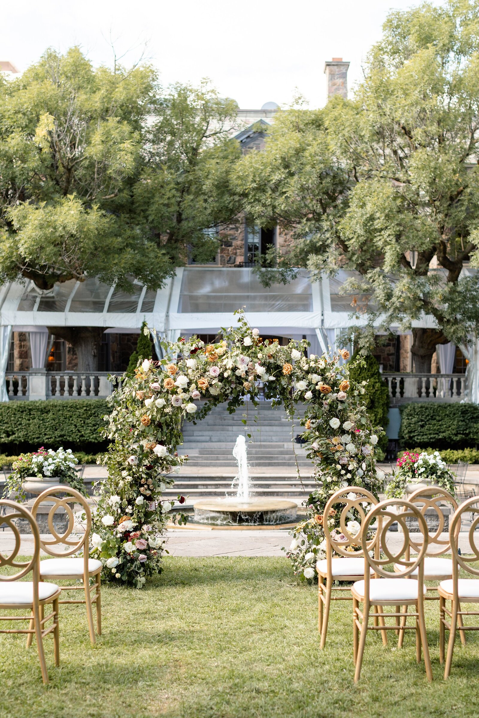 Outdoor-ceremony-floral-arch-with-gold-chairs-at-graydon-hall-manor