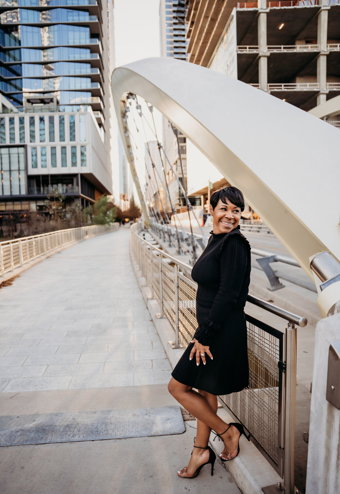 Branding Photographer, a woman in dress and heels leans on a city bridge