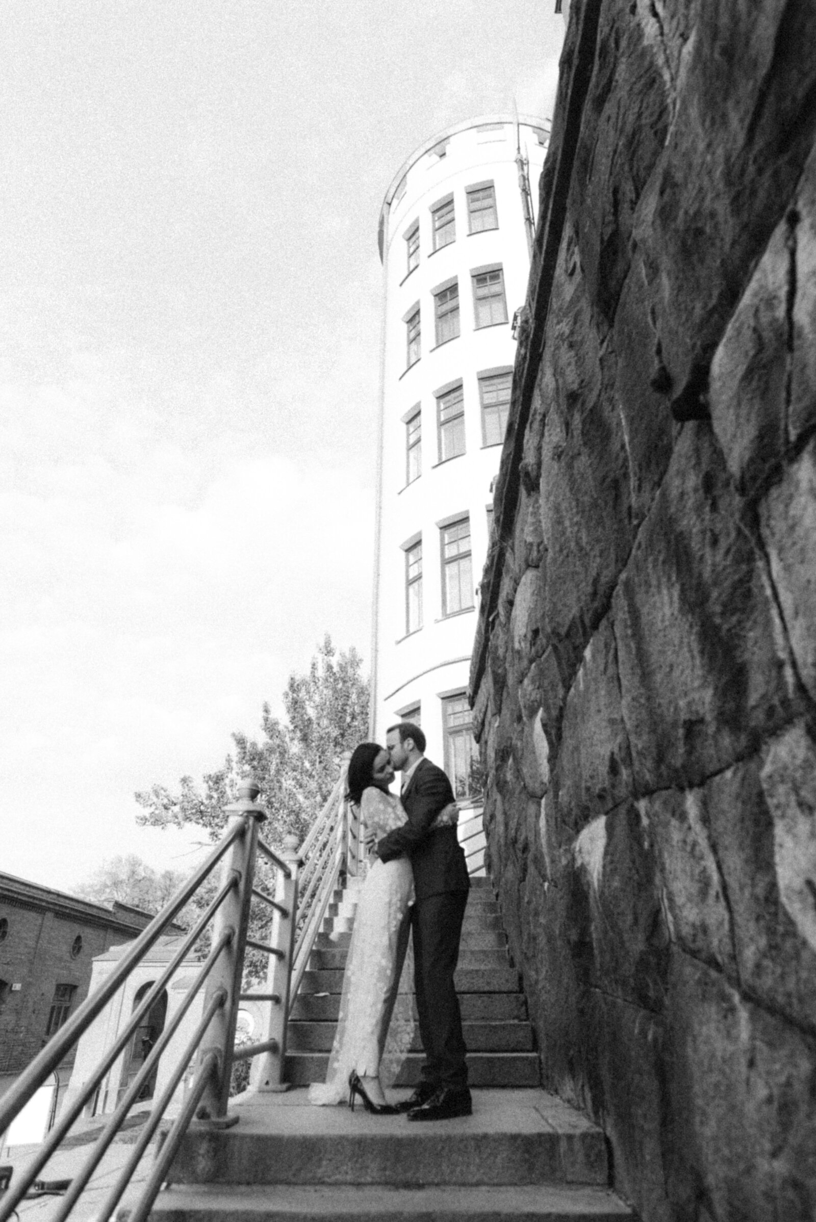 Urban wedding photography by a Scandinavian wedding photographer Hannika Gabrielsson. A wedding couple is hugging on the stairs in front of a building.