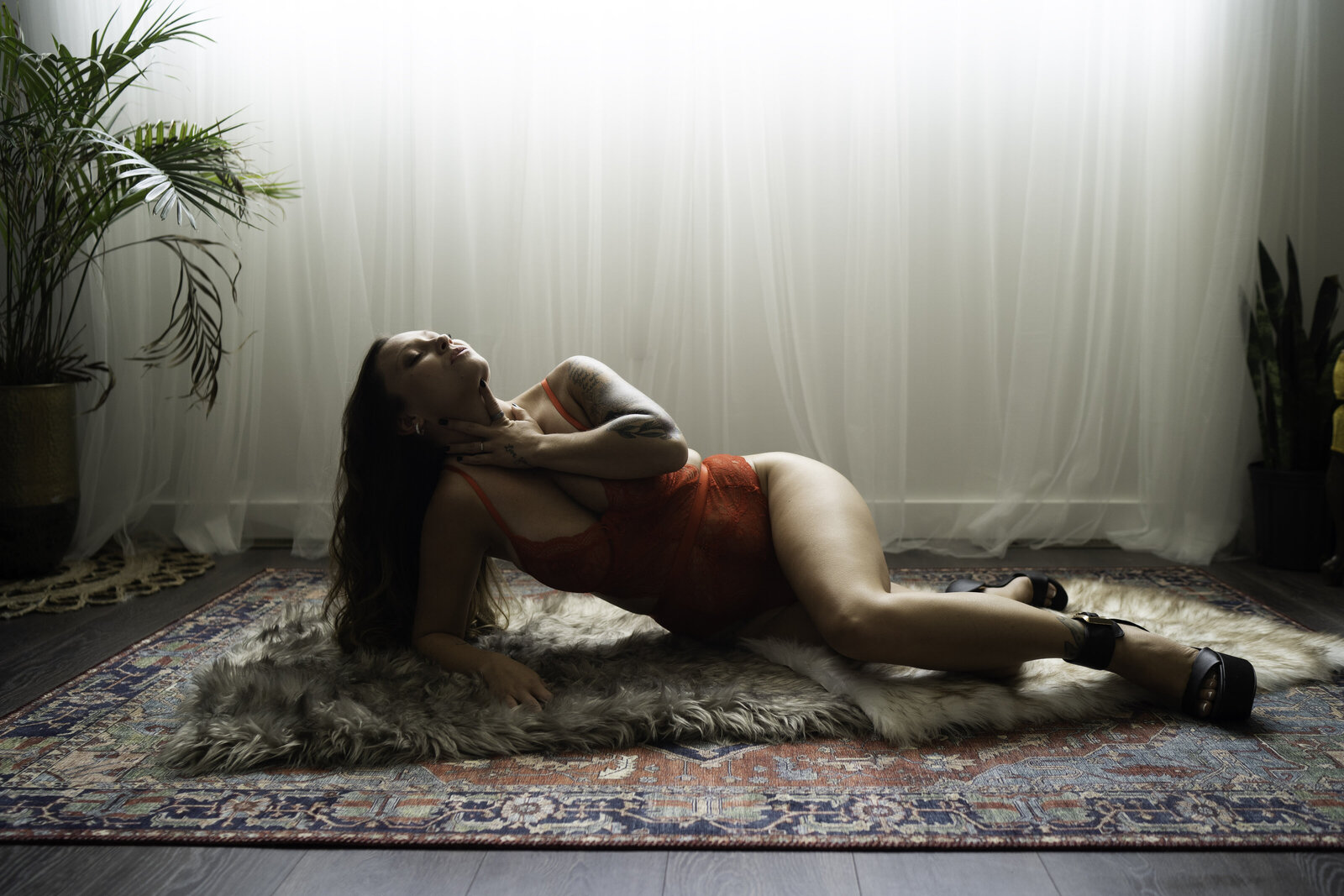 Woman lying on an oriental rug below a large window full of natural light.
