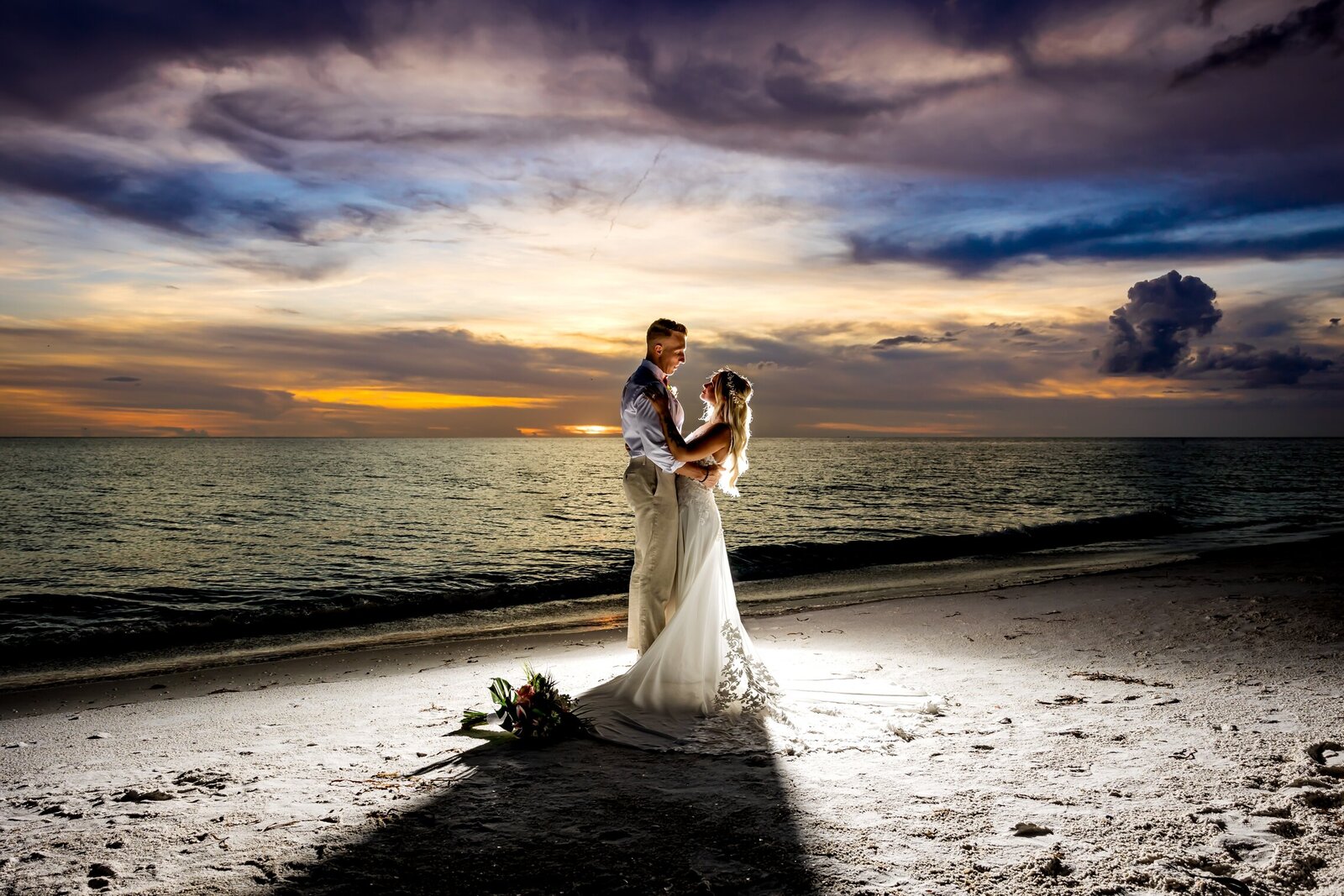 Bride and groom embracing backlit with a flash after sunset on Anna Maria Island, Fl.