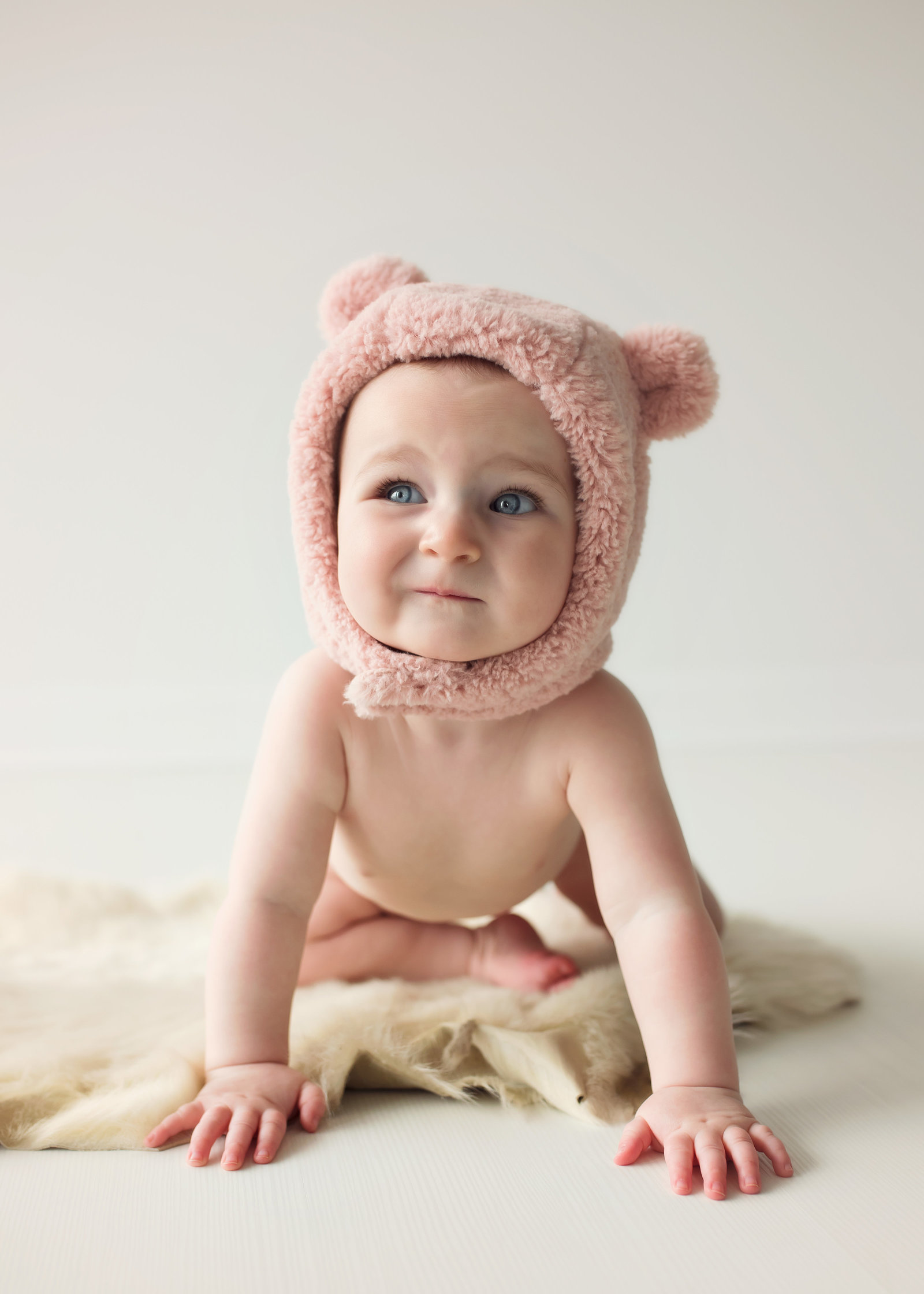photo of baby in bear hat in studio making funny face