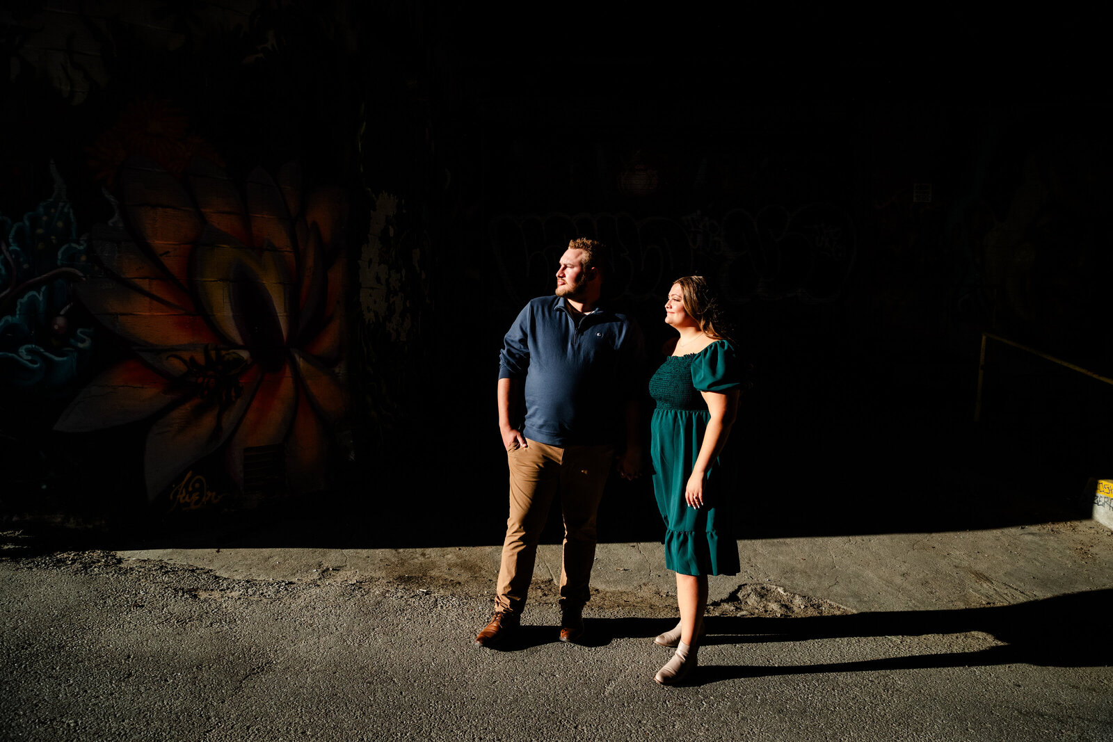 Engaged couple looking into the sun in a alley