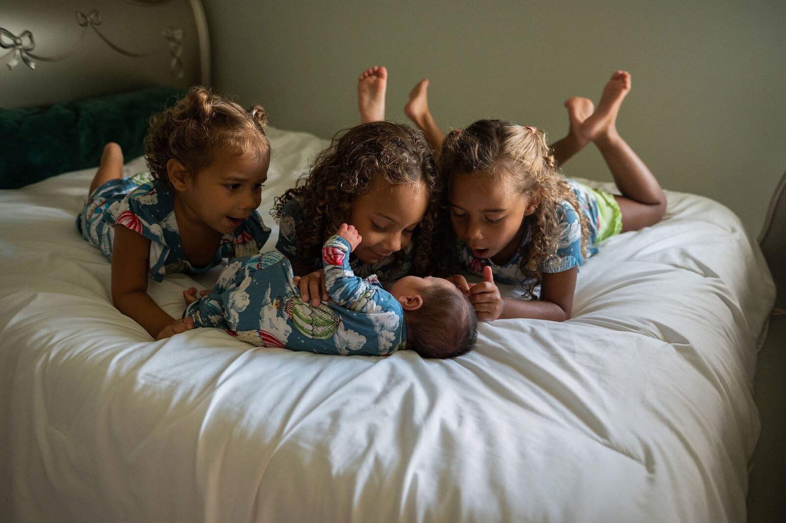 girls around baby sister on bed in Pensacola, Florida home