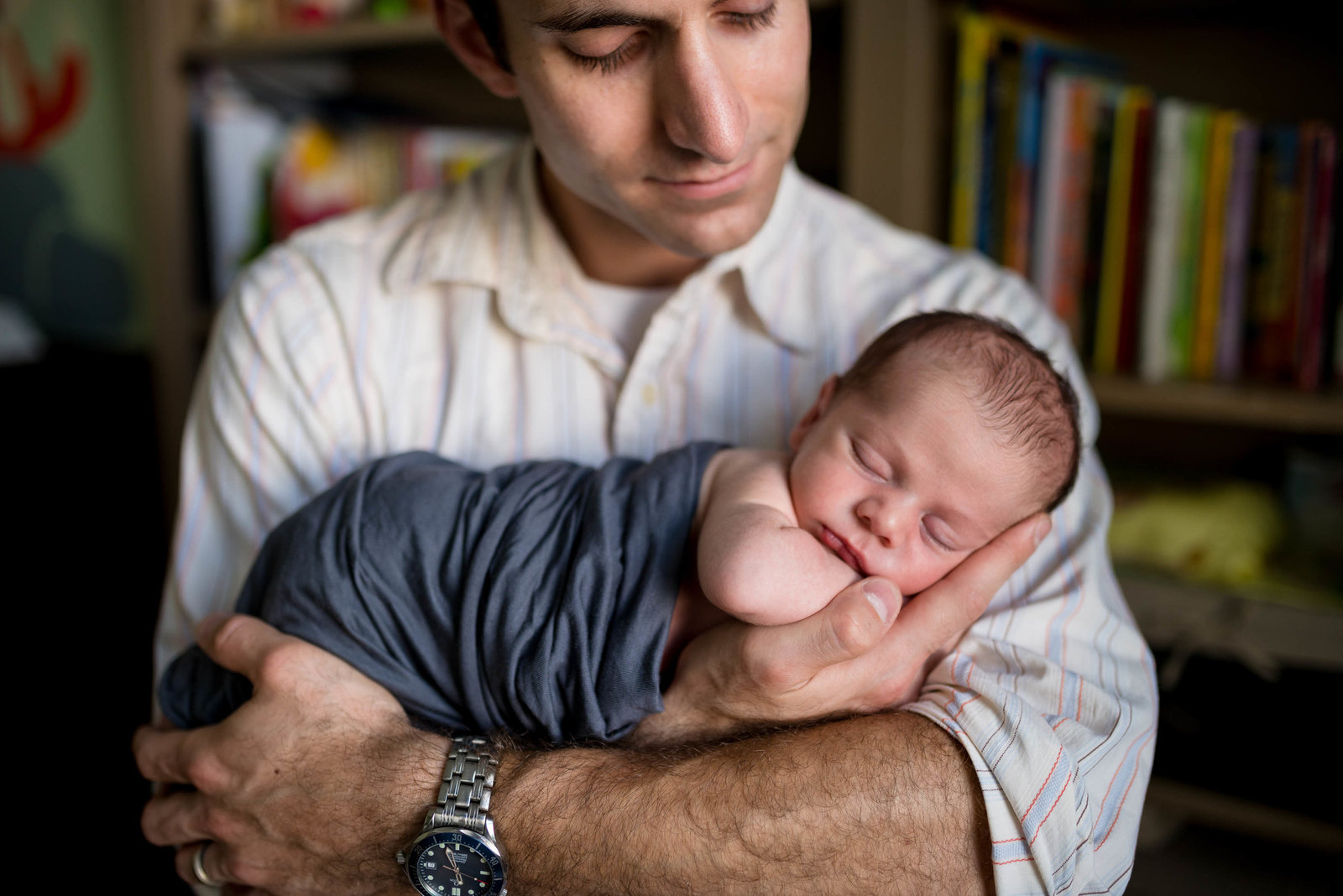 Newnborn at home in father's hands in Boston lifestyle home session