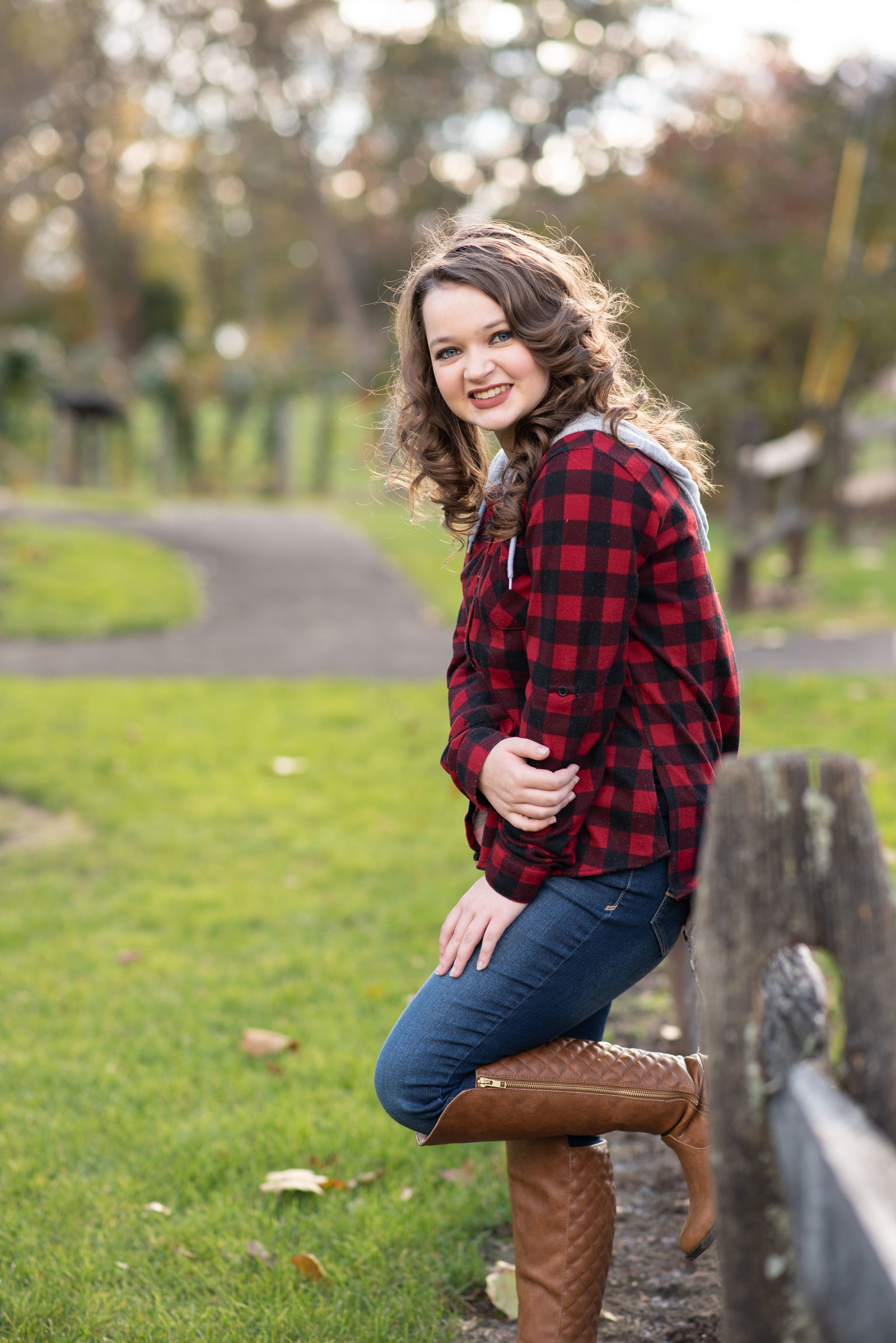 Teen Girl in buffalo plaid leaning against fence
