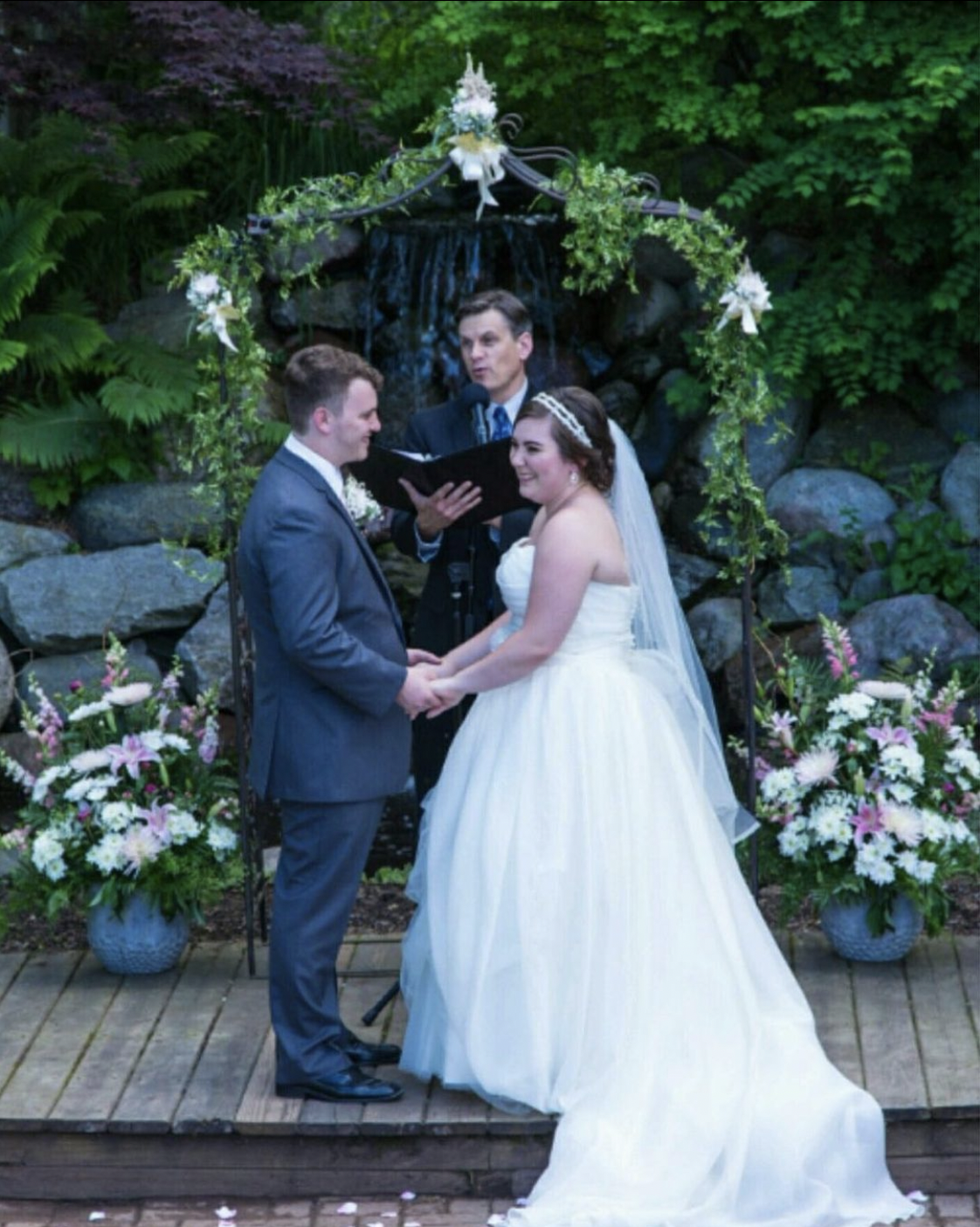 Bride and groom hold hands during outdoor wedding ceremony