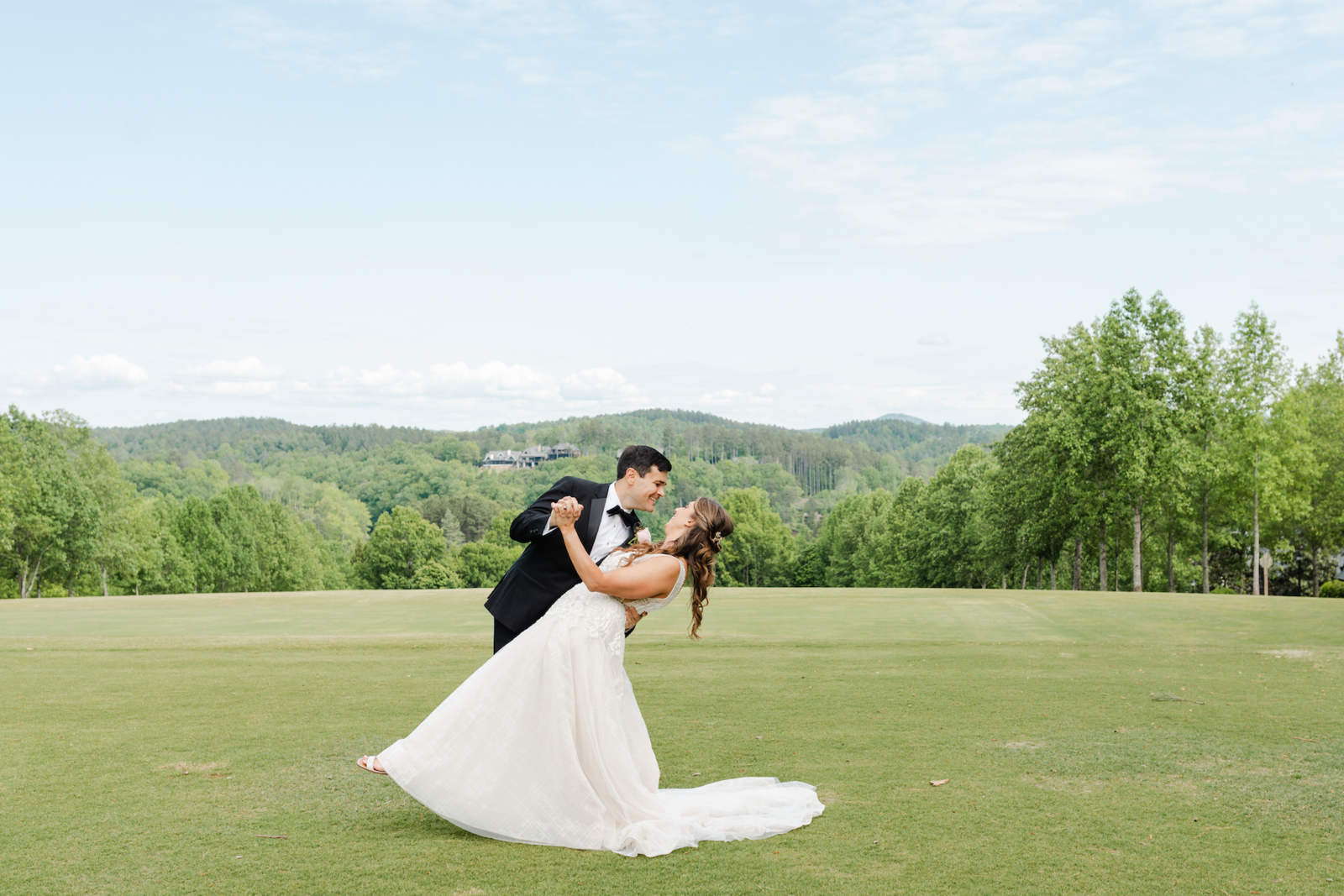 Groom dipping his bride with mountain scape in the background