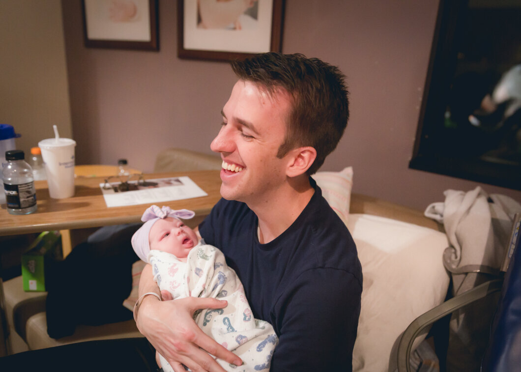 A bran new father laughs as he meets his daughter. Birth Story session by Diane Owen Photography.