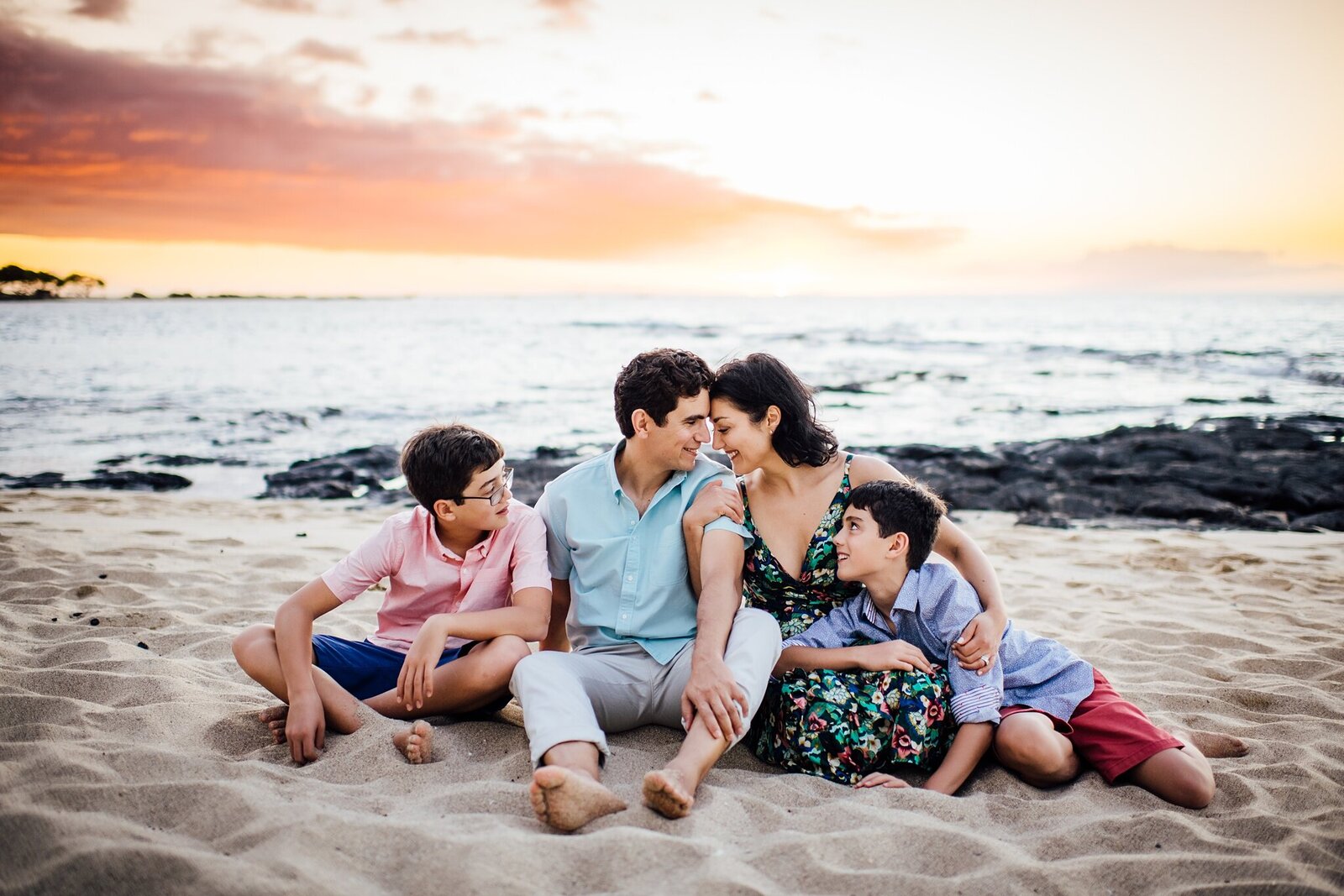 beautiful family sitting on the beach at sunset