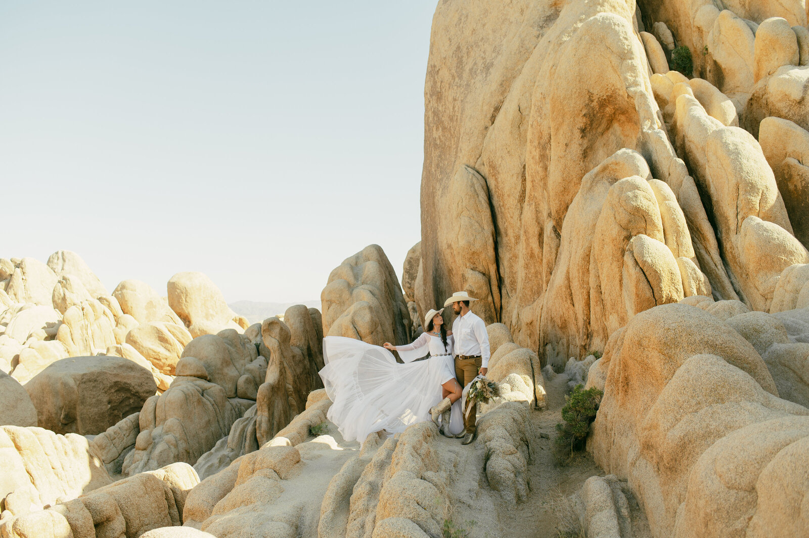 An Elopement on Joshua Tree's Arch park; a bride swings her dress in the wind.