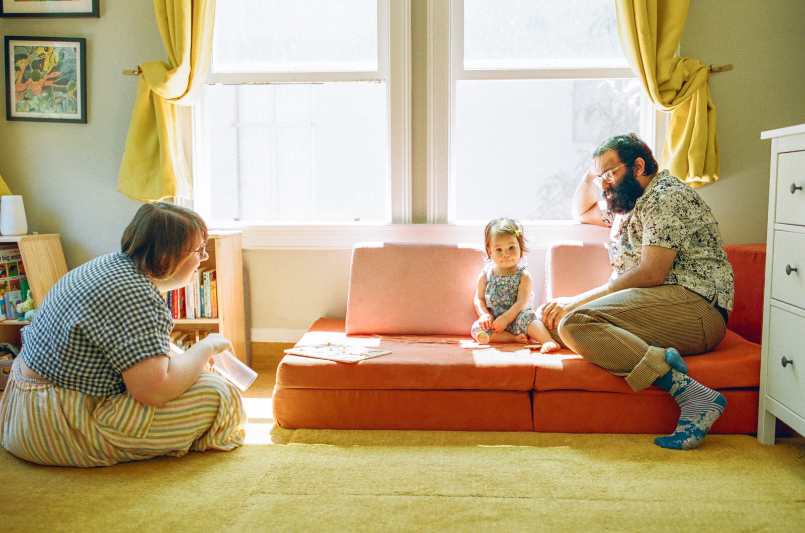 photo of family sitting on and around a pink nugget couch in nursery