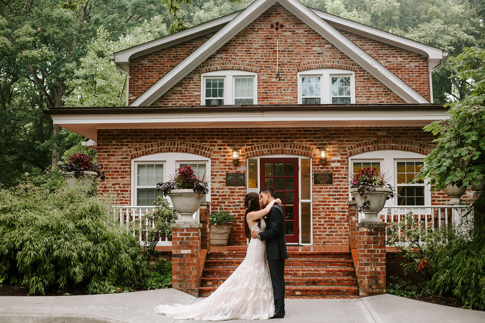 Bride and groom holding each other in front on an old brick home