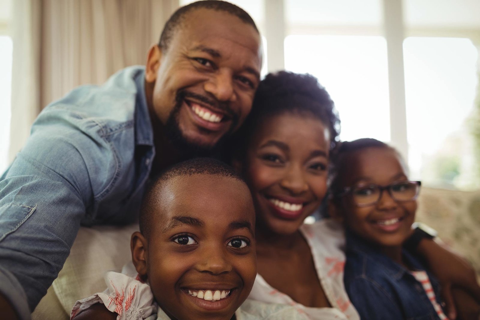 Family portrait of a Black mother and father smiling with their two children, capturing a moment of togetherness. Celebrate family bonds with Successful Black Parenting Magazine.