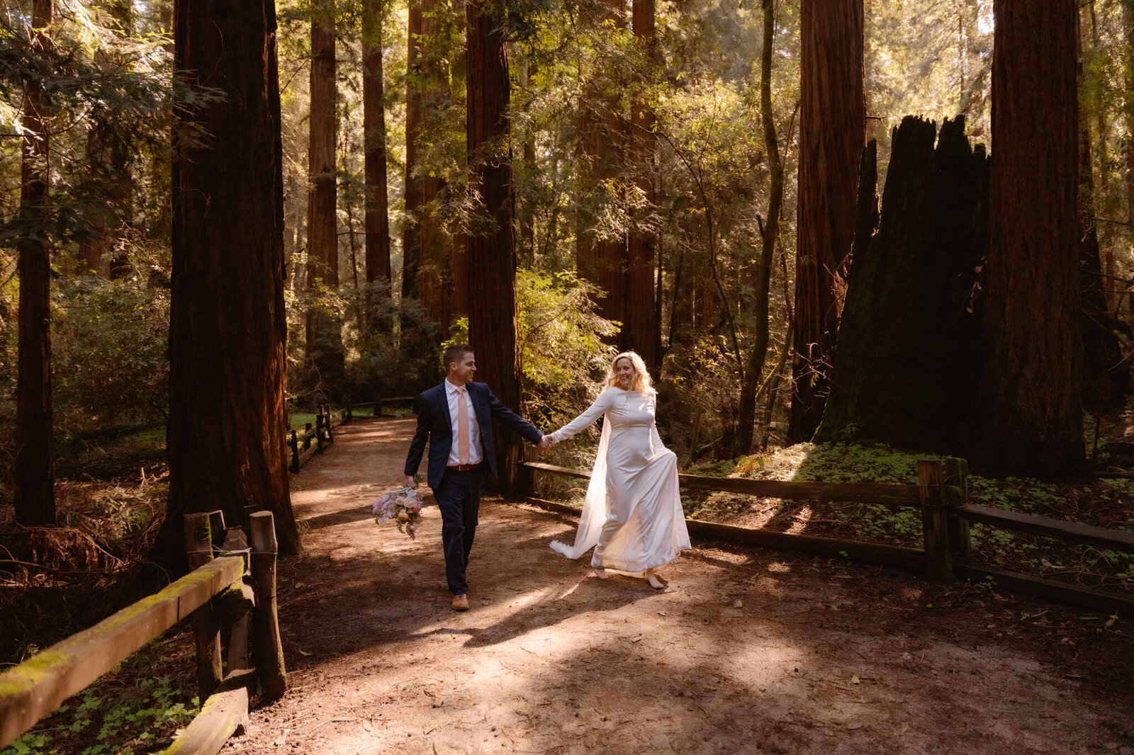 Bride and groom walking barefoot through the redwoods after their elopement in Redwood National Park.