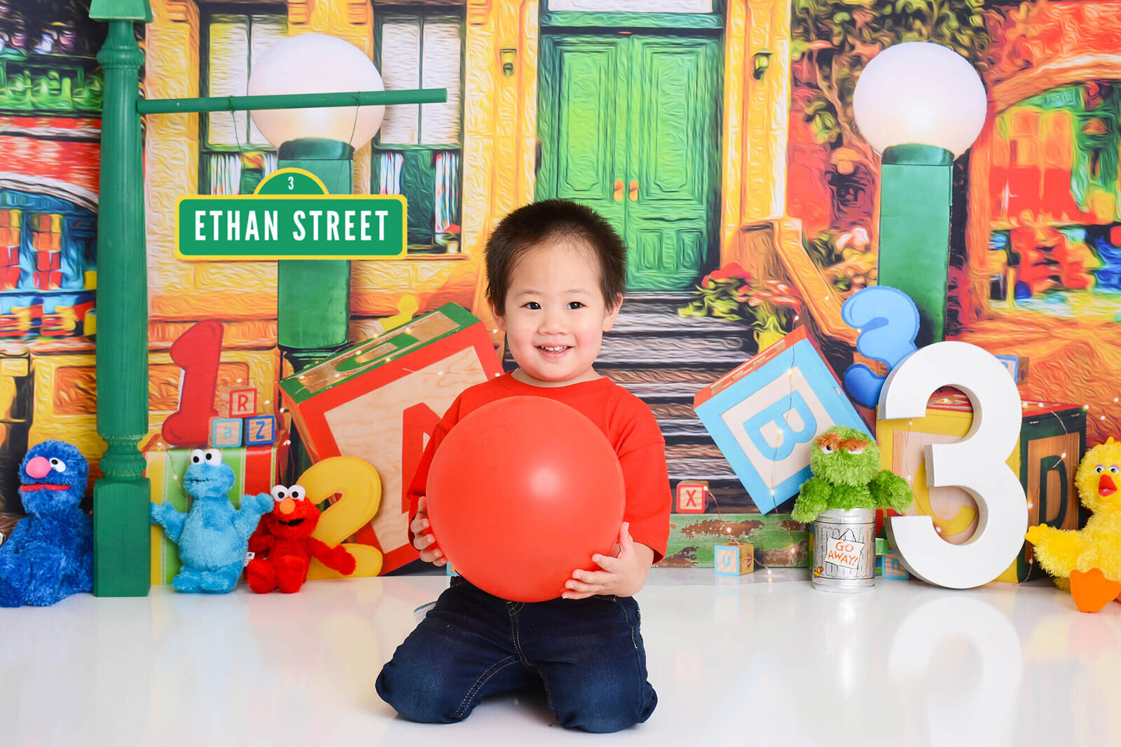 boy smiles at the camera at a photo studio in houston with a sesame street background