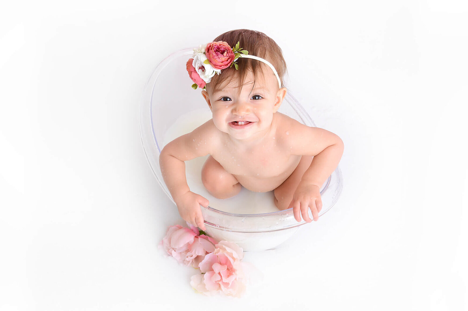 girl smiles while in a milk bath at her first birthday photoshoot in houston