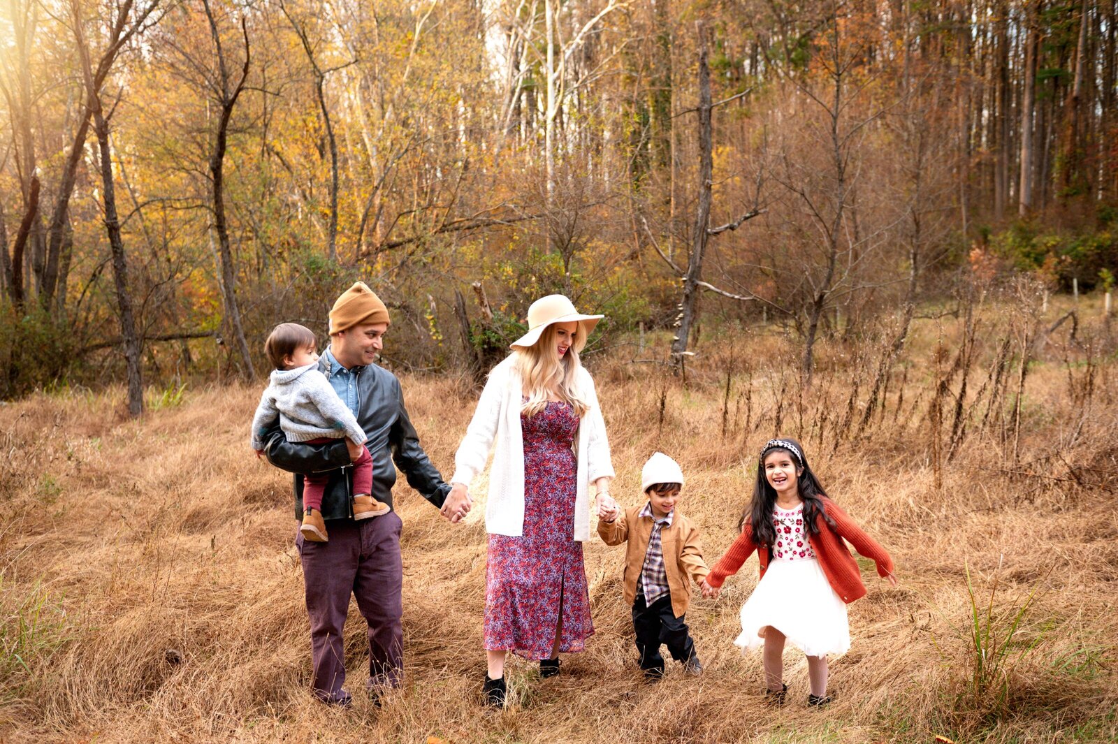 Family of 5 holding hand walking in the grass field