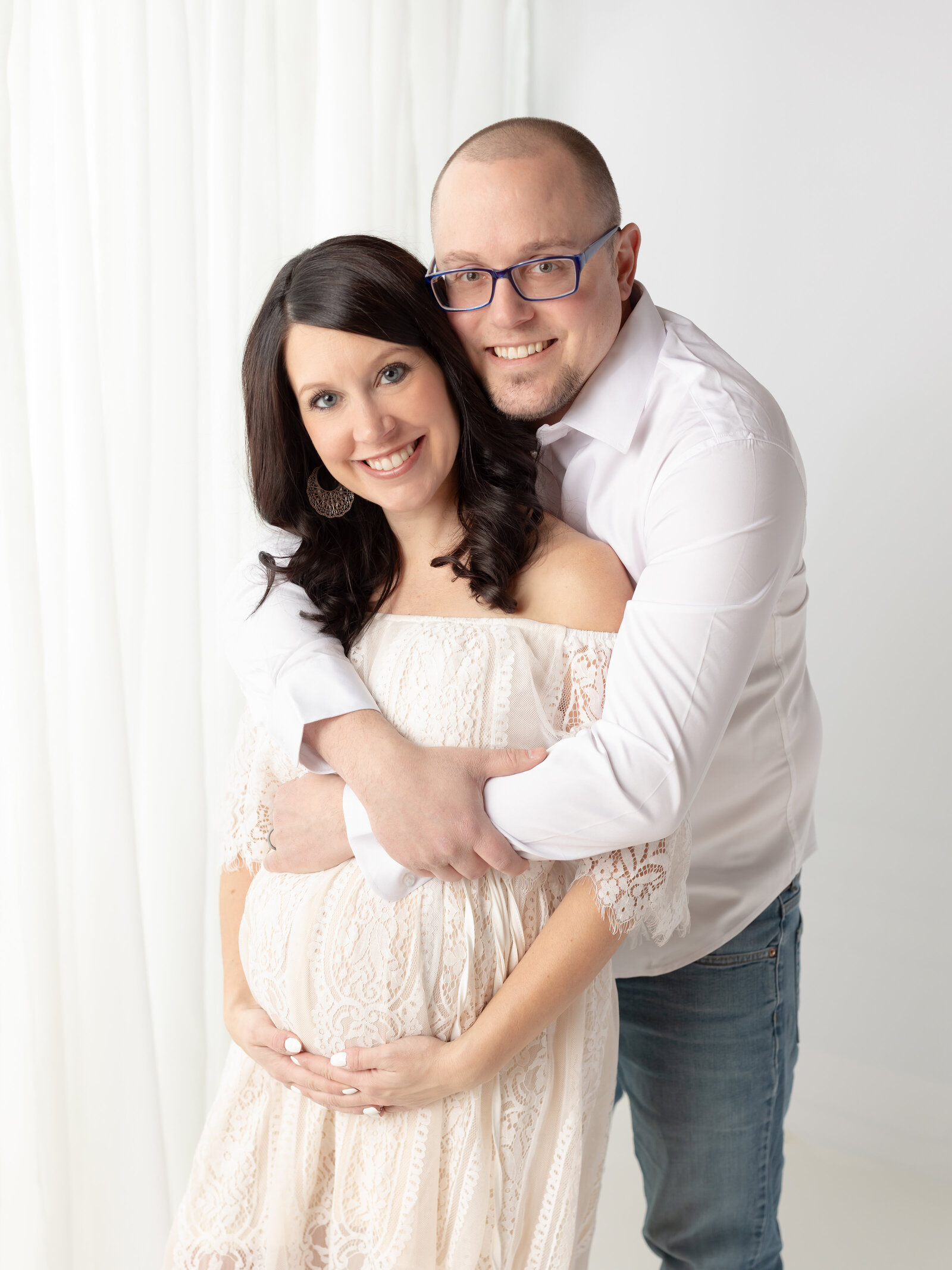 husband hugging pregnant wife in white lace dress for maternity photos Cleveland Maternity Photographer