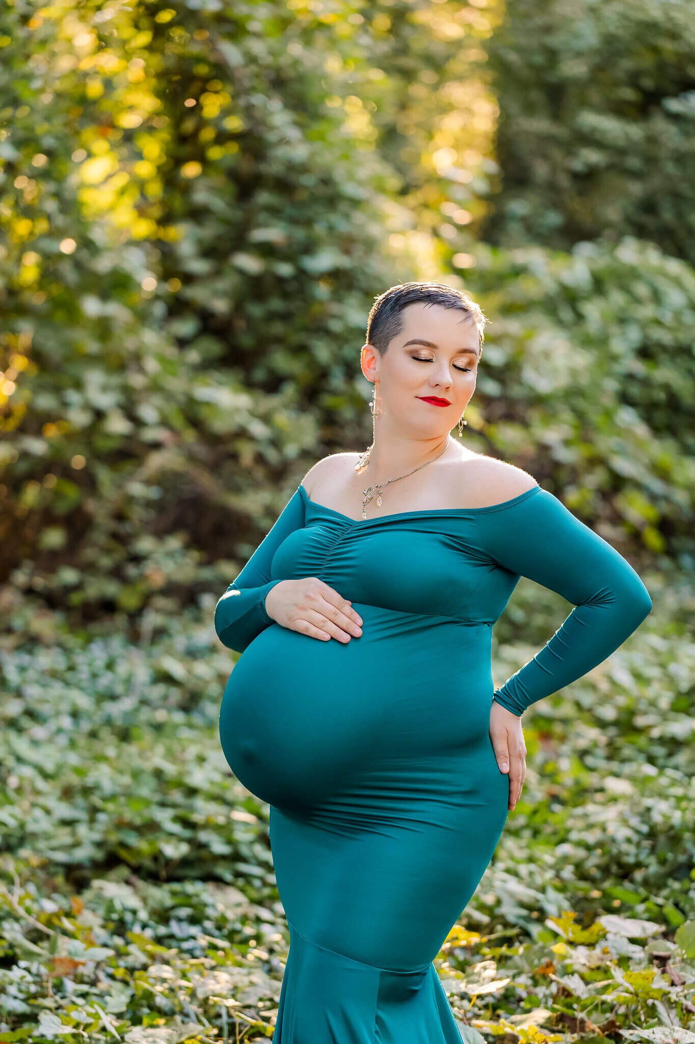 A mother-to-be posing in an Alexandria park wearing a teal dress.