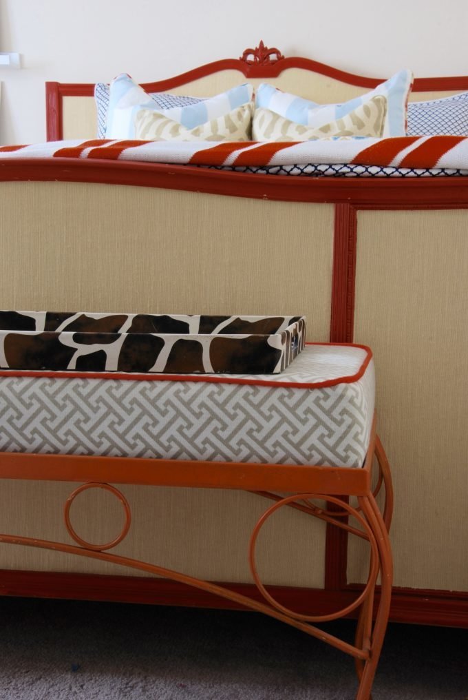 An orange iron bench in front of a footboard.