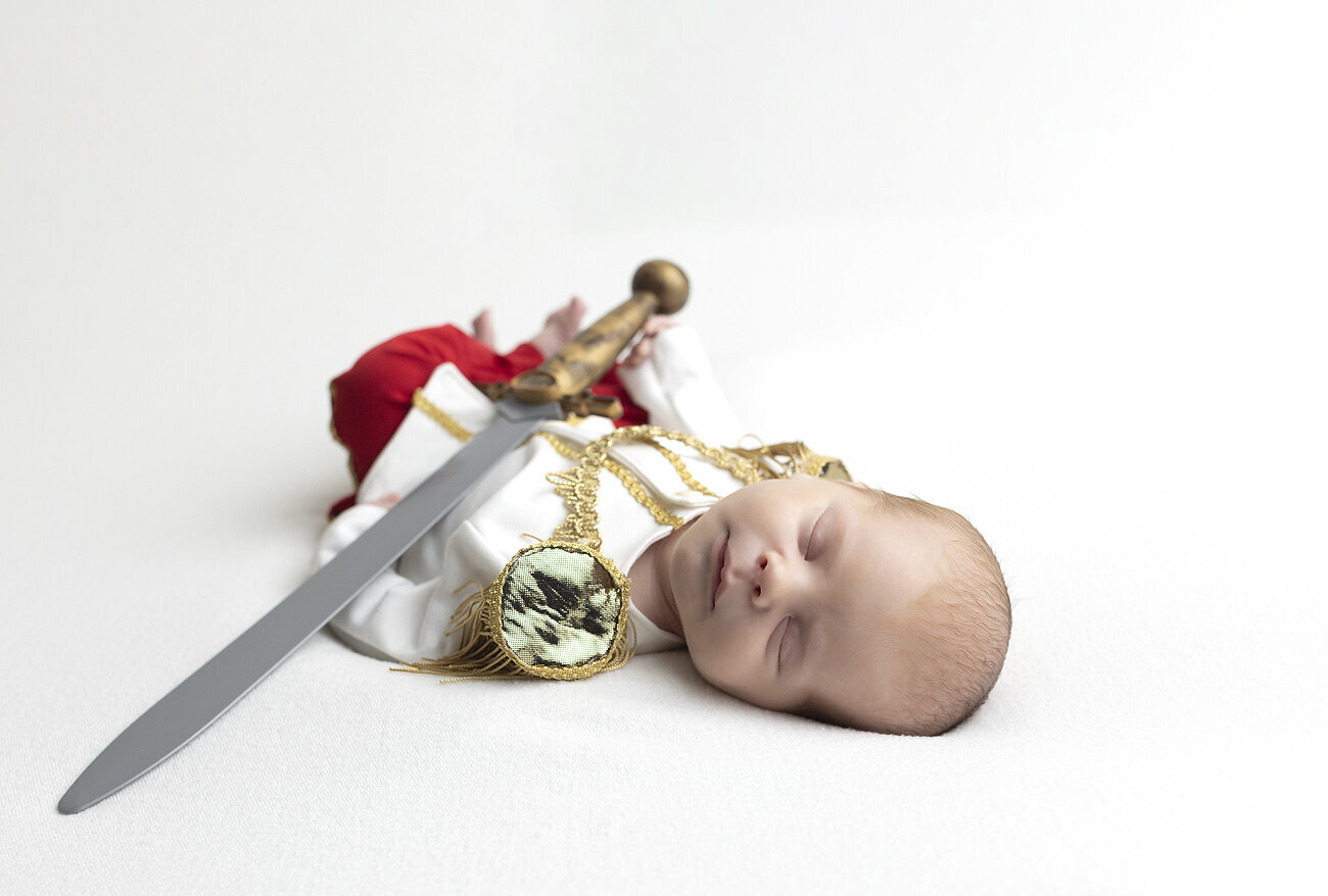 Newborn boy dressed as prince charming.